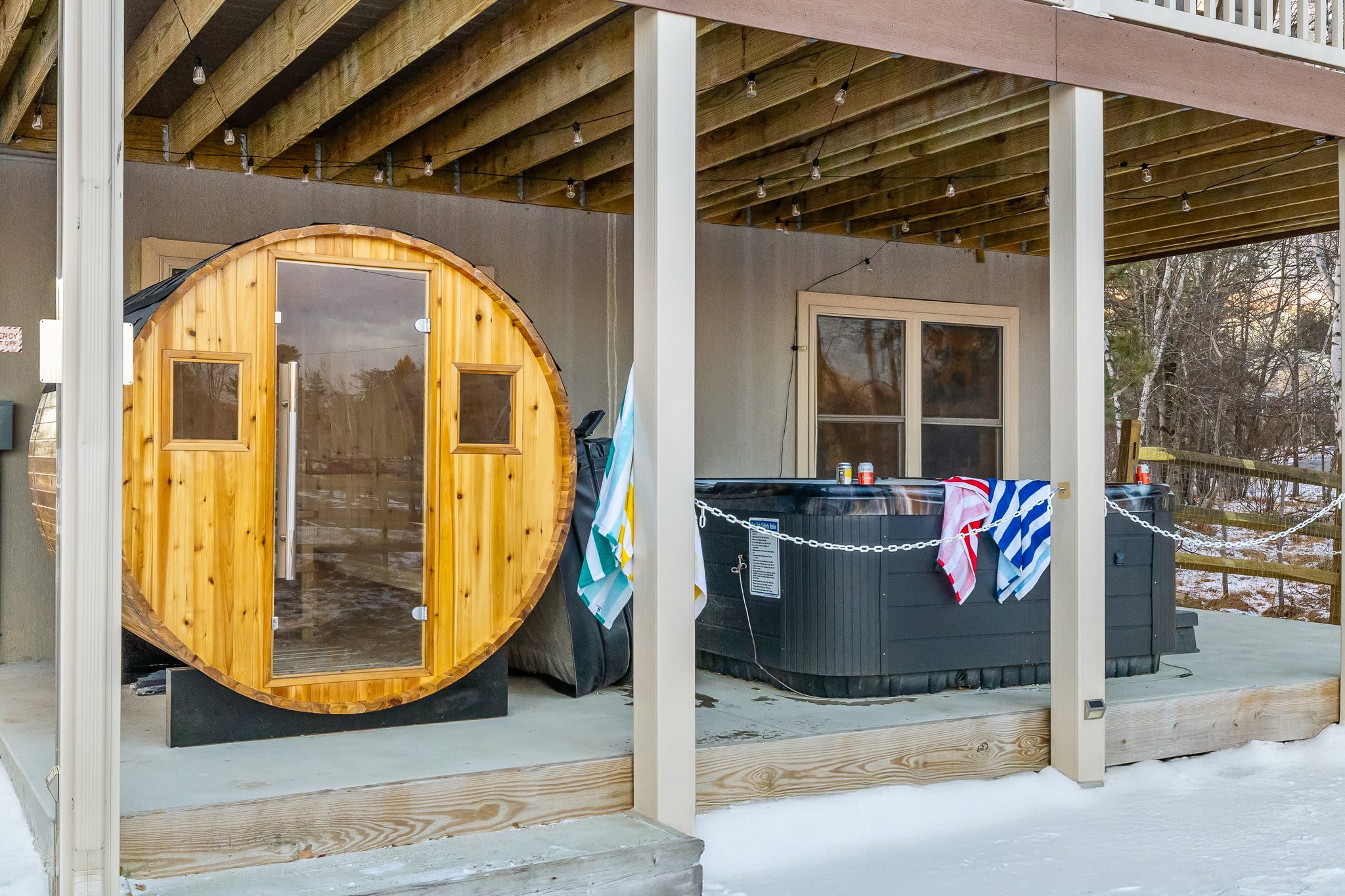 Your private wellness station featuring a cedar sauna and hot tub tucked beneath the deck, cozy and secluded even in the snow.