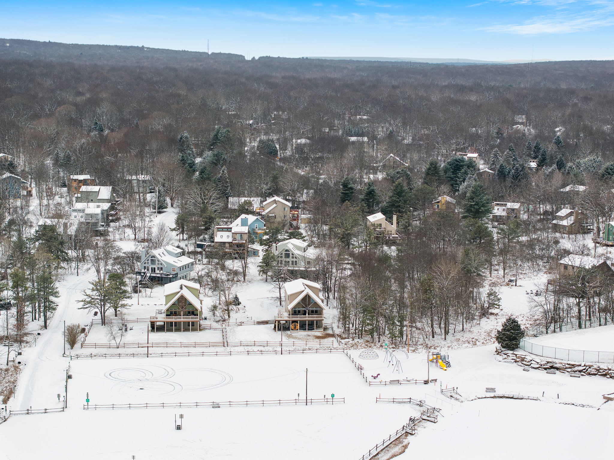 Scenic drone view of the neighborhood with rooftops and trees dusted in snow. The perfect serene setting for a winter retreat.