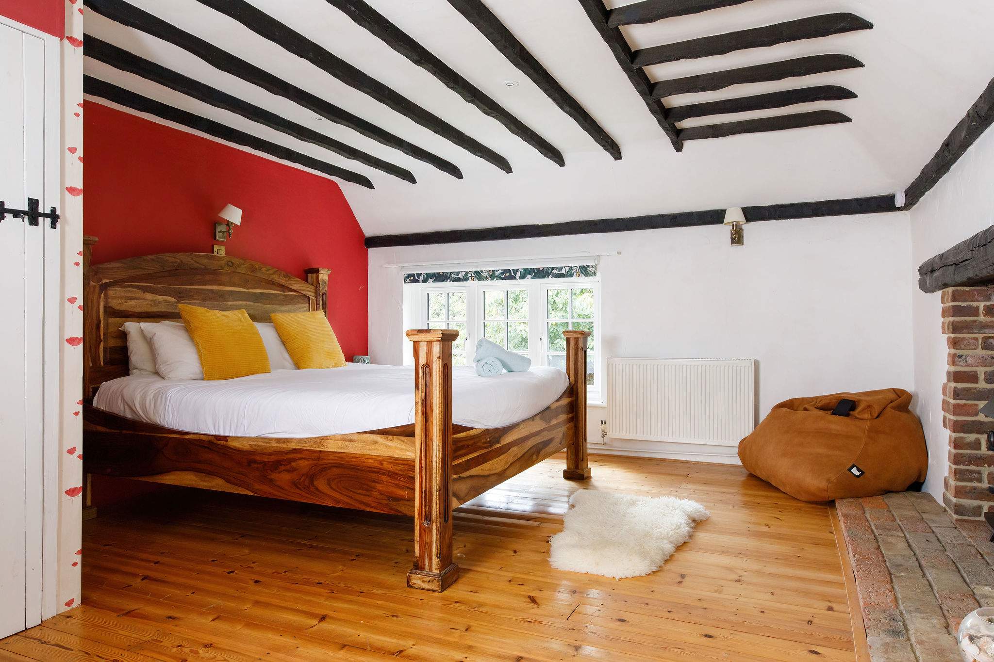 This master bedroom has many original features, such as a fireplace, wooden beams and flooring.