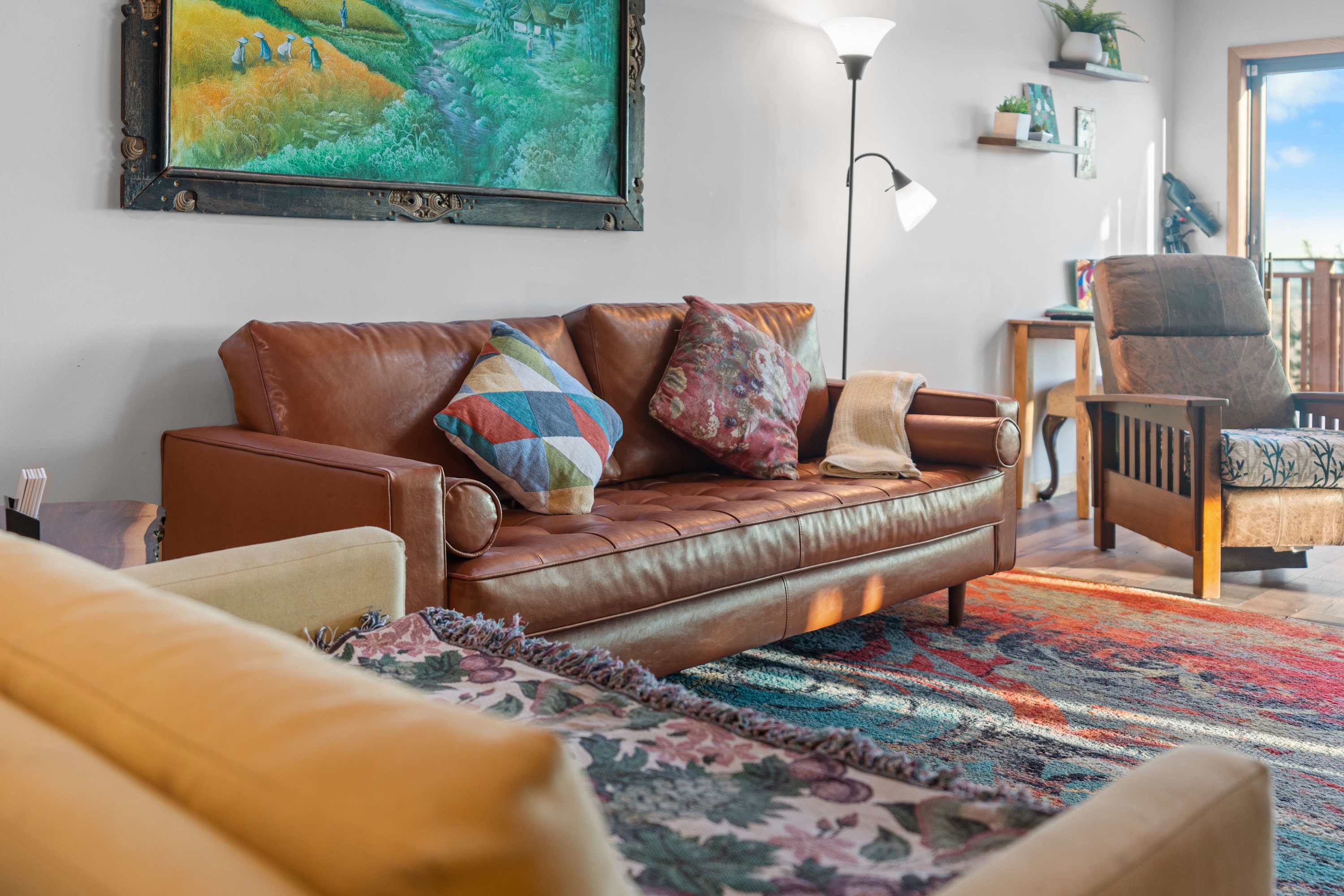 That leather couch and colorful pillows give the room such a warm and inviting feel! The mix of textures and the cozy seating arrangement make it perfect for relaxing. 