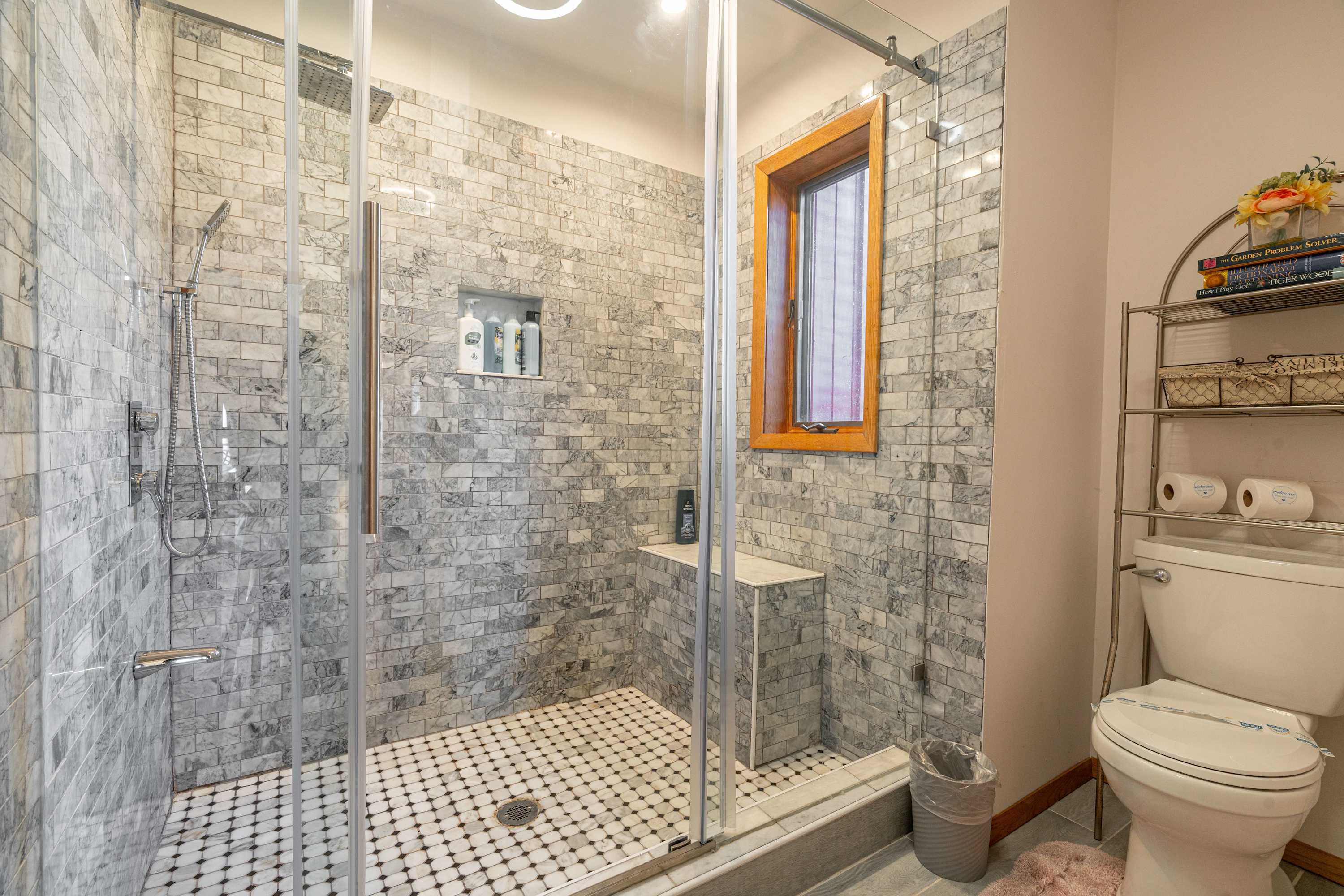 Spacious and elegantly designed bathroom with a walk-in shower, marble-style tiling, and modern fixtures for a luxurious experience.