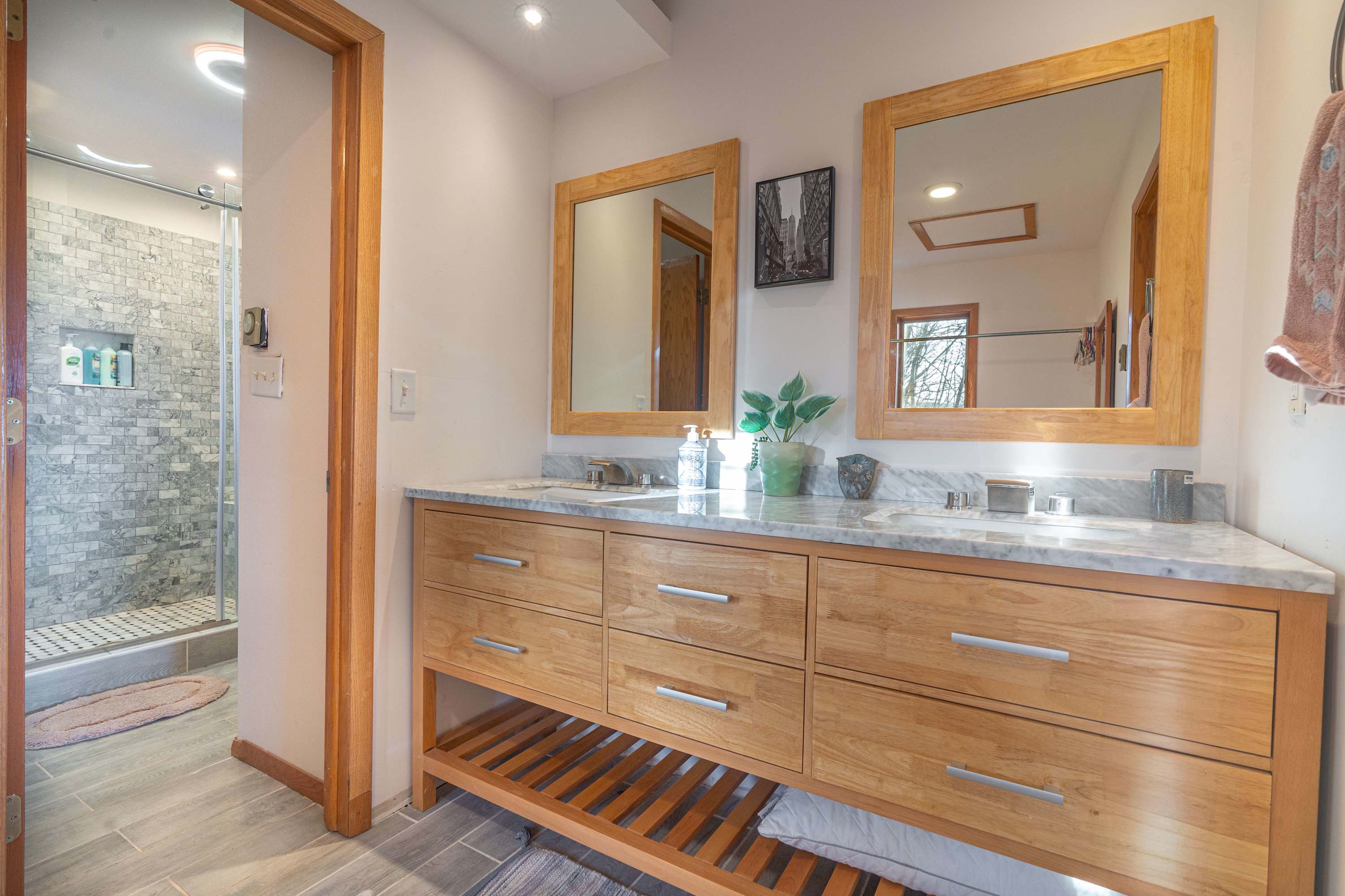 Modern bathroom with a spacious double vanity, marble countertop, and warm wood accents, offering both style and functionality.