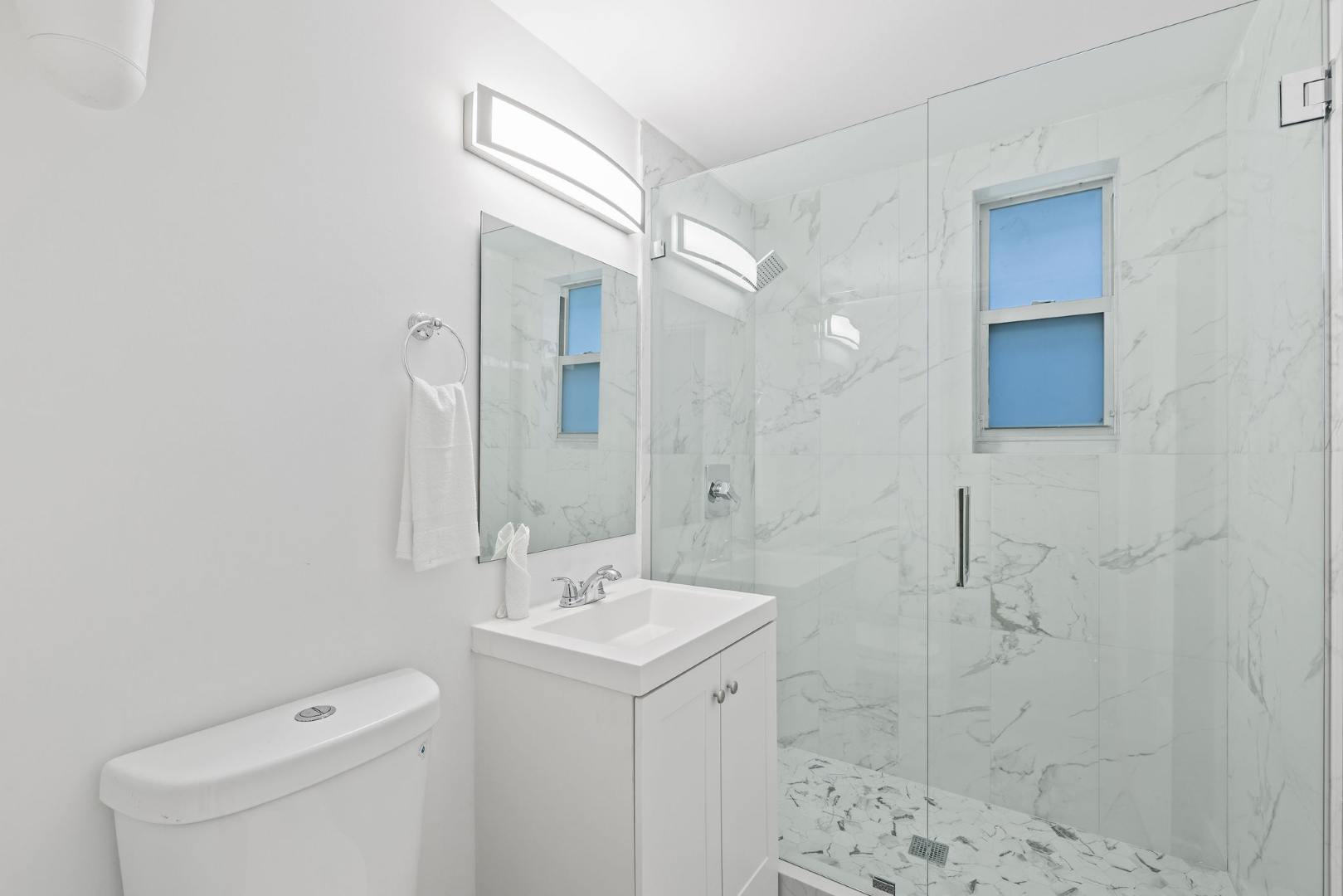 Experience luxury in this sleek, marble-tiled bathroom with a spacious glass shower and modern fixtures.