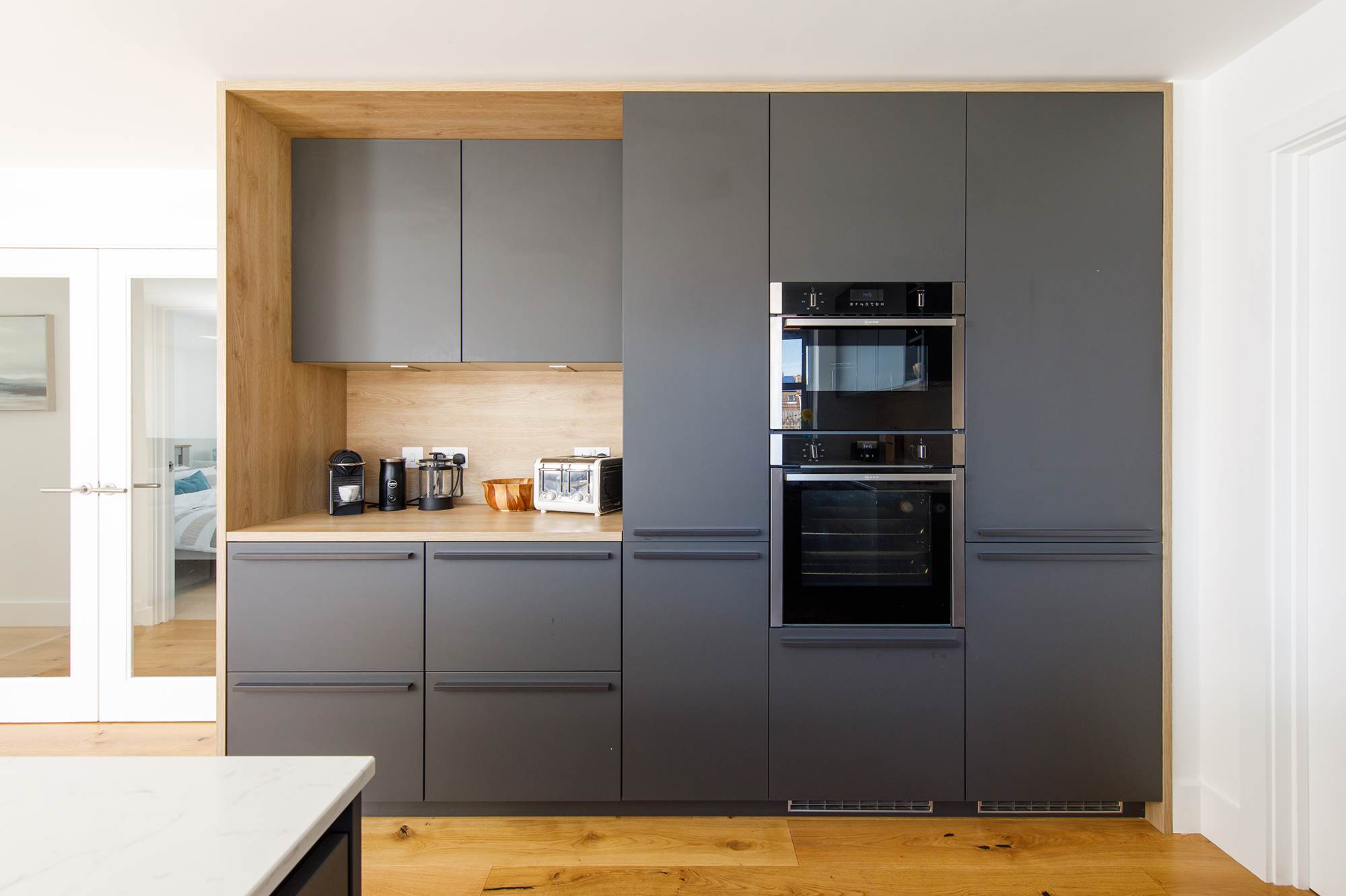 The kitchen features a sleek, contemporary design in dark grey tones.