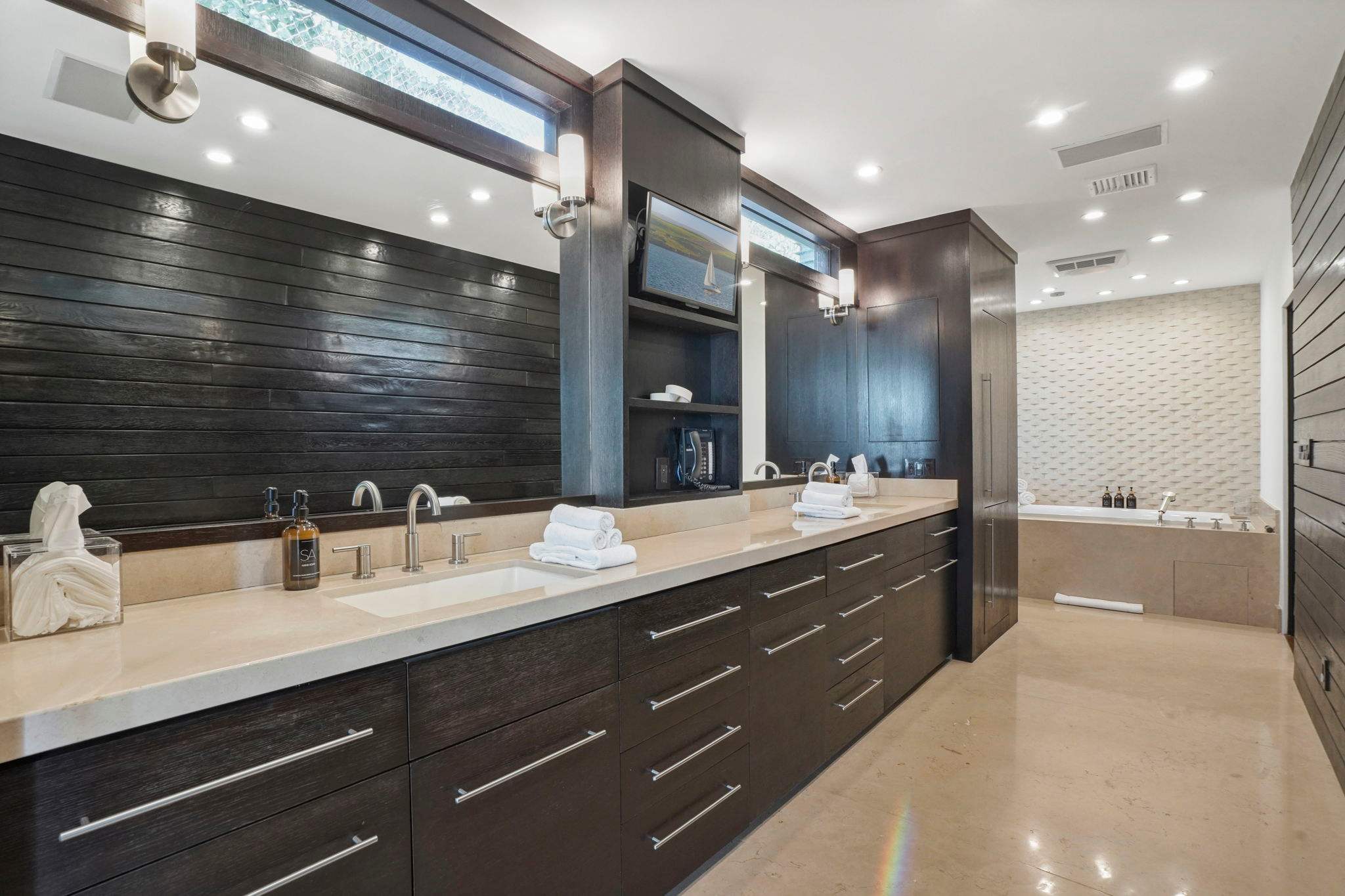 Dual vanities with sleek stone counters and rich wood cabinetry.