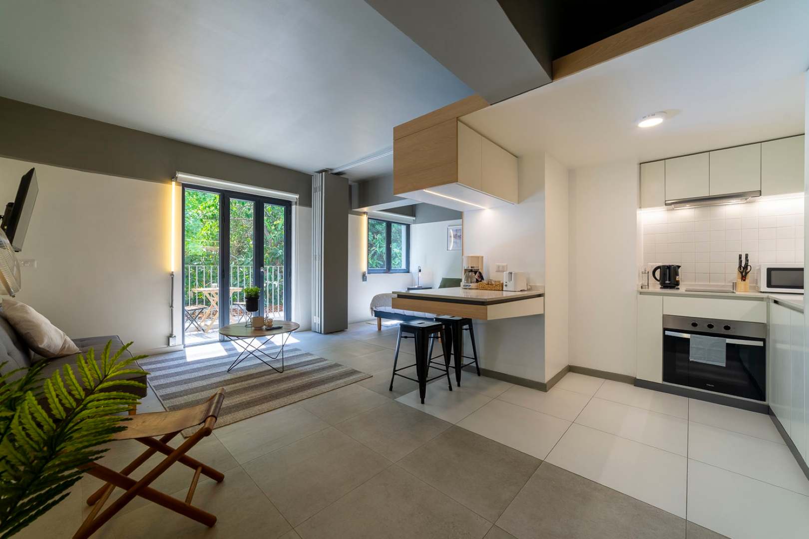 Enjoy cooking in a modern, compact kitchen with natural light and a view of lush greenery from the balcony.