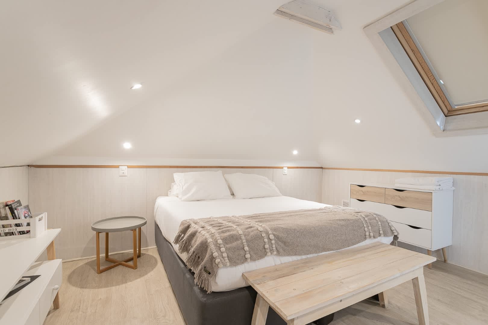 Relax in this charming attic bedroom, featuring a cozy bed under a skylight, perfect for stargazing and unwinding.