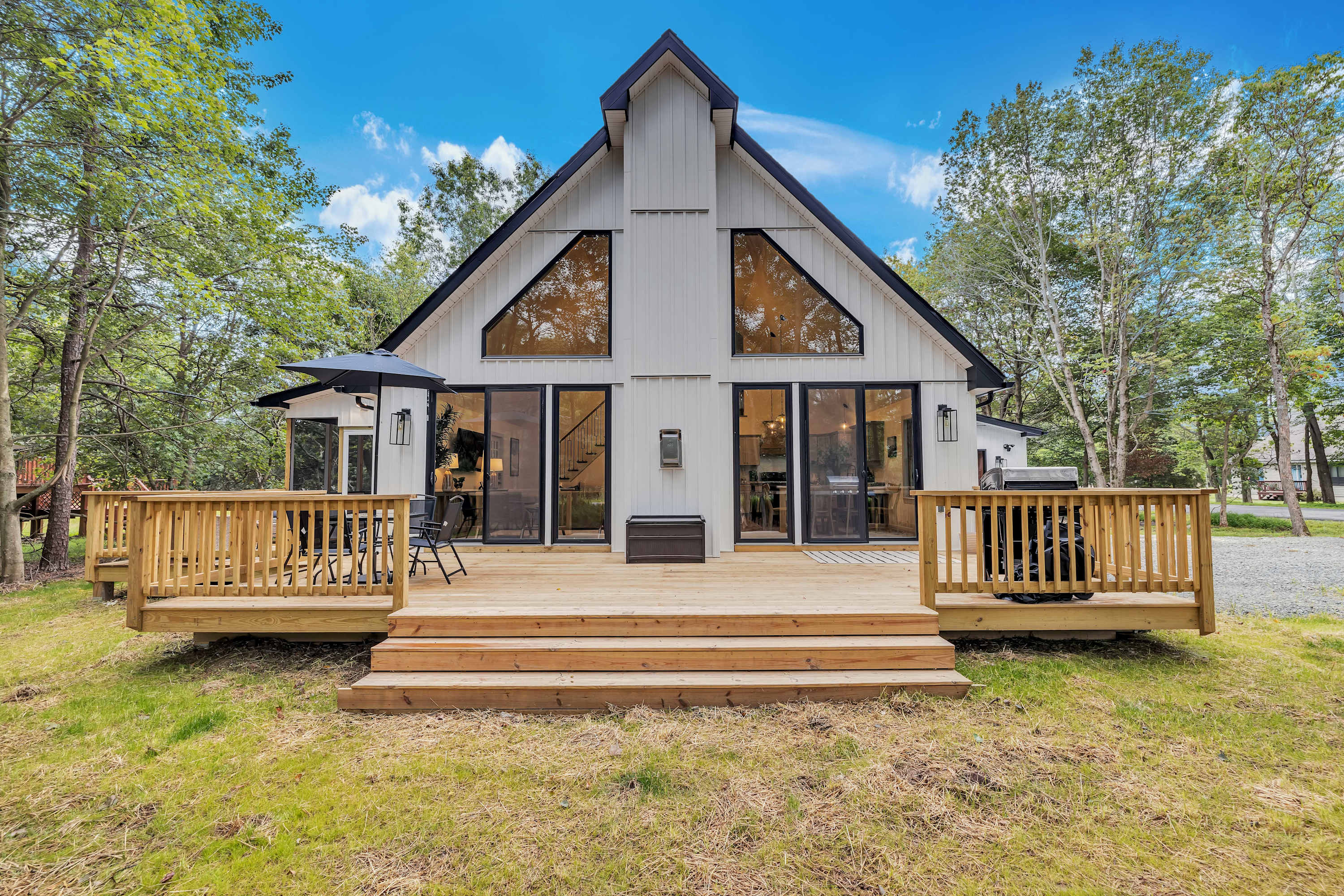 A-Frame Cabin Charm – This stunning modern A-frame home features a spacious deck and a warm, inviting exterior perfect for a cozy getaway.