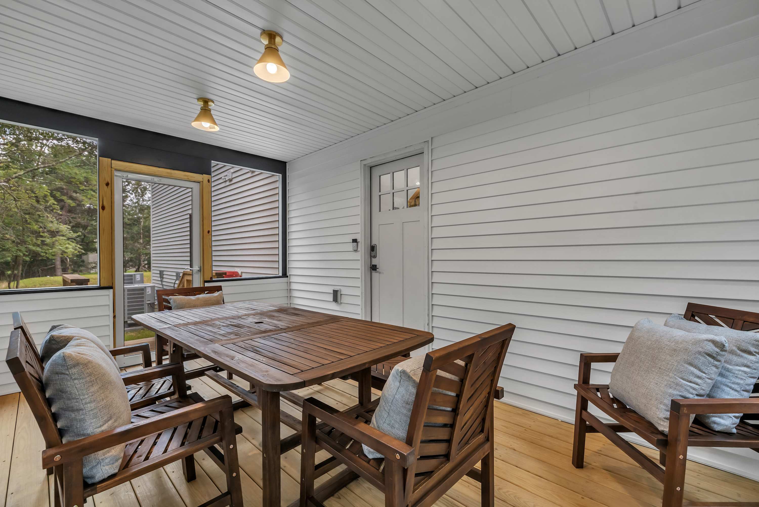 Charming Enclosed Patio Dining – A beautiful screened-in dining area with warm lighting, perfect for enjoying meals in a cozy and intimate setting.