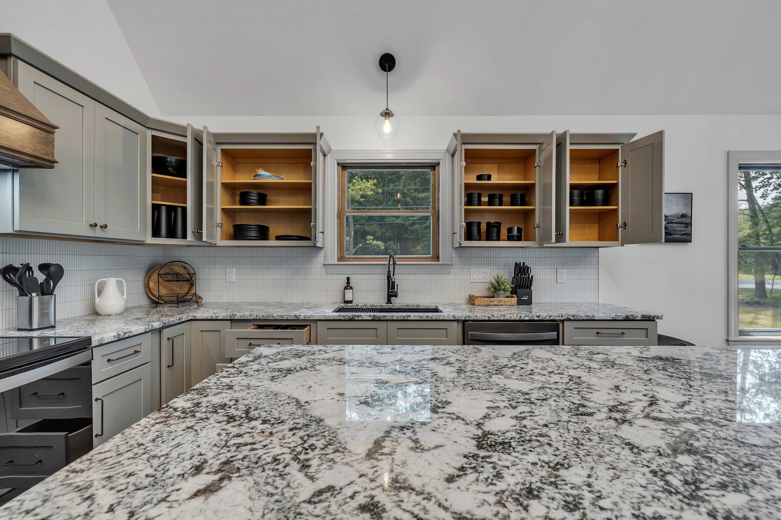 Sleek & Spacious Kitchen Design – A stunning granite island takes center stage in this chef’s kitchen, complemented by warm cabinetry and modern lighting.