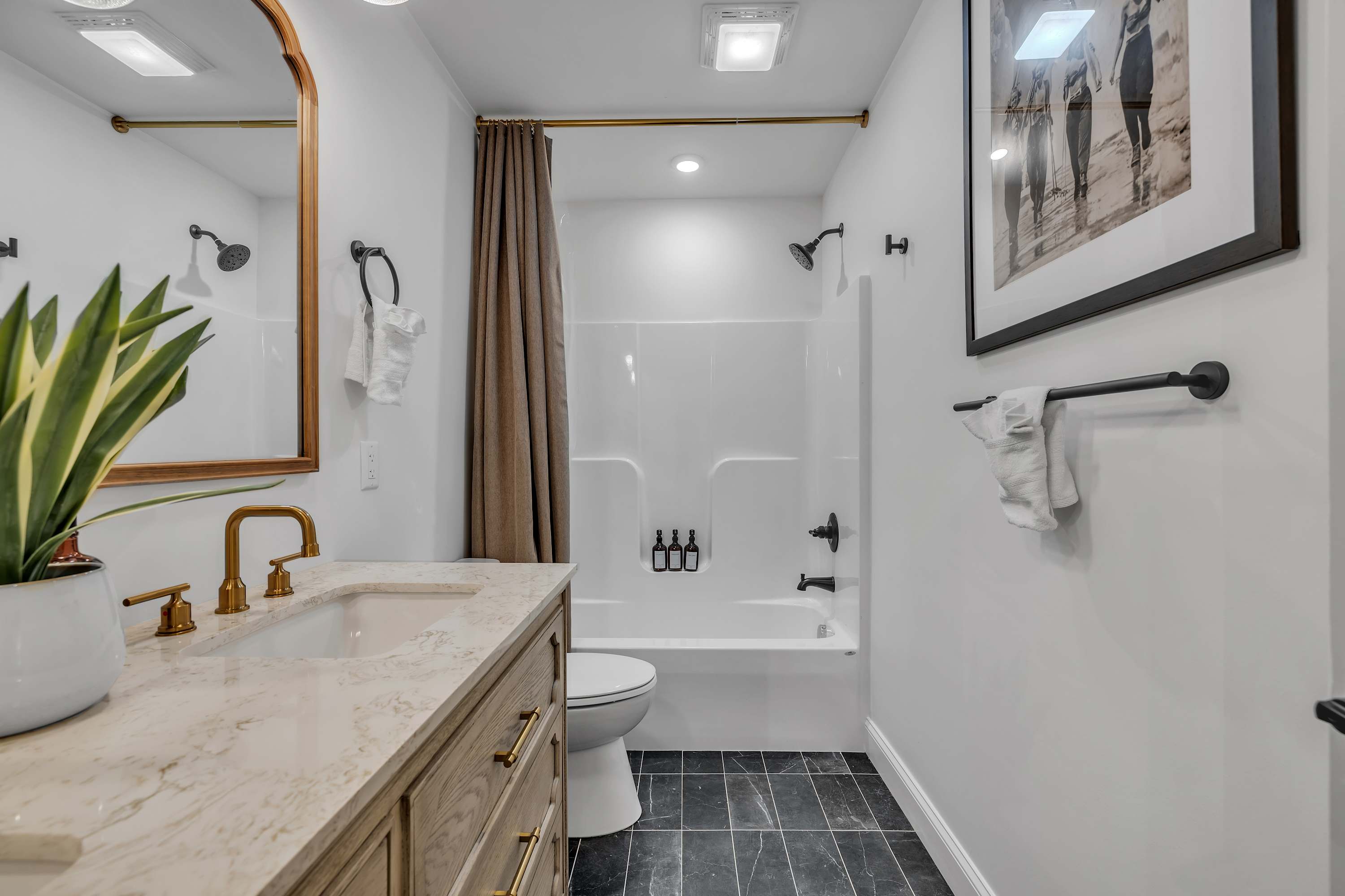Bright & Modern Bath Space – A stylish bathroom with sleek black tile floors, a spacious vanity, and a combination shower and tub for ultimate relaxation.