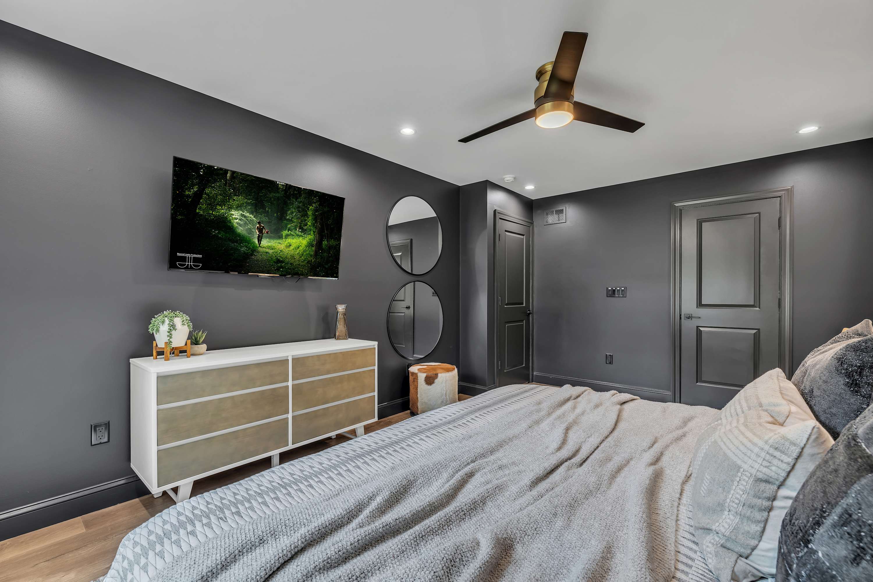 Spacious & Cozy Bedroom Retreat – A sleek and modern bedroom featuring a wall-mounted TV, ceiling fan, and ample storage for a relaxing stay.