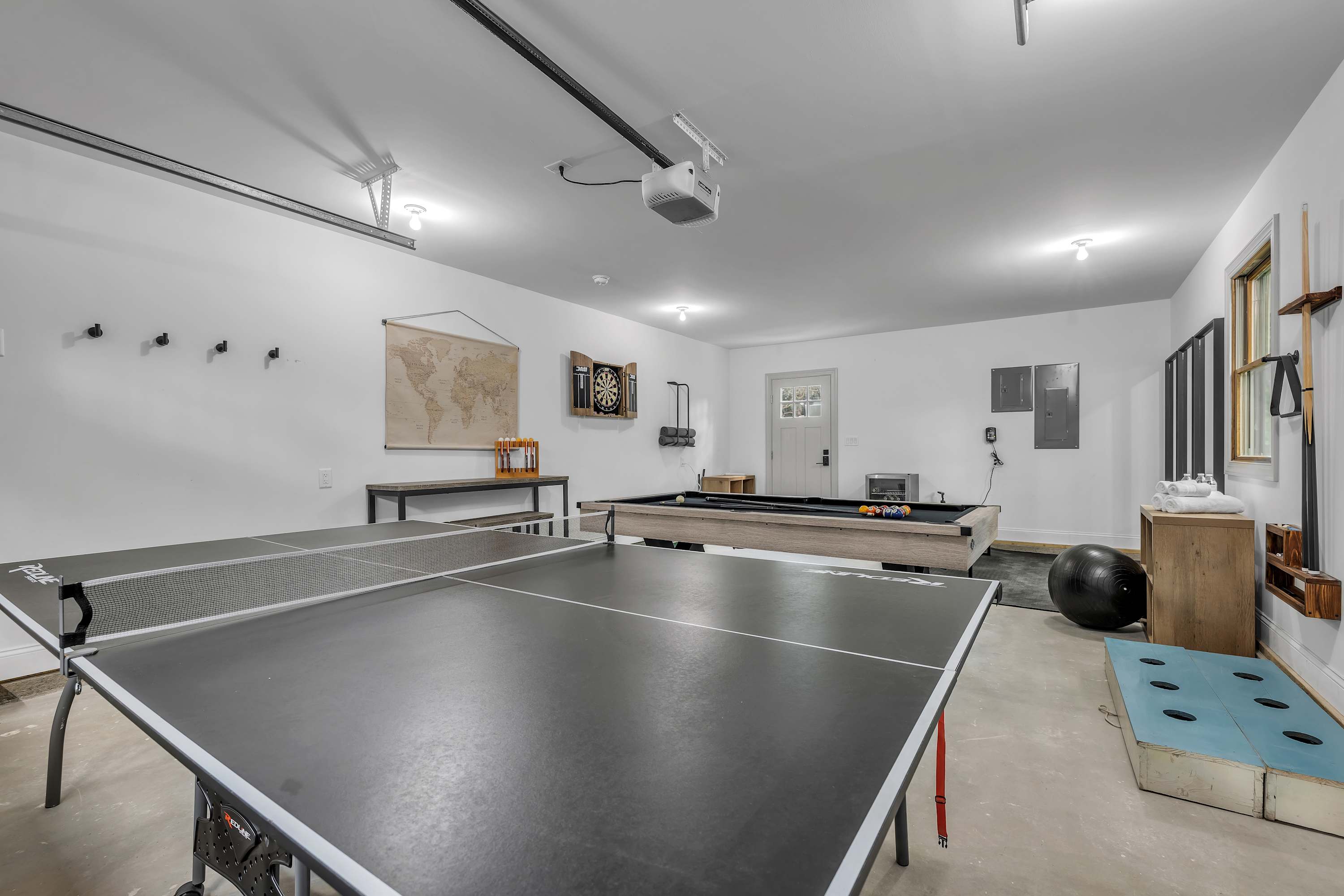 Ping Pong & More Fun Awaits – A bright and open game room with a full-sized ping pong table, workout equipment, and plenty of space to unwind.