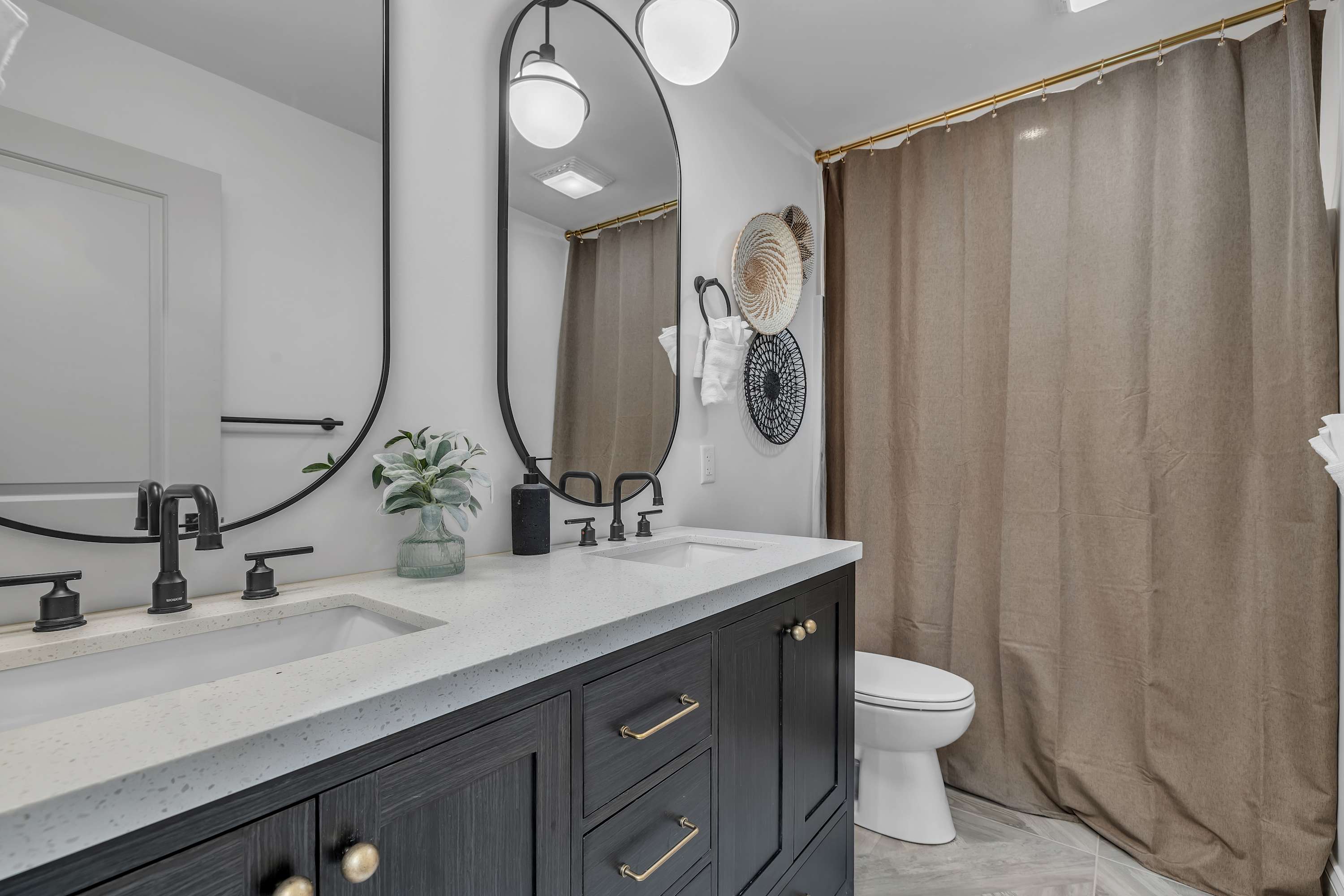 Elegant & Spacious Bathroom – A sleek double vanity with bold cabinetry, gold accents, and modern lighting, creating a refined and luxurious feel.