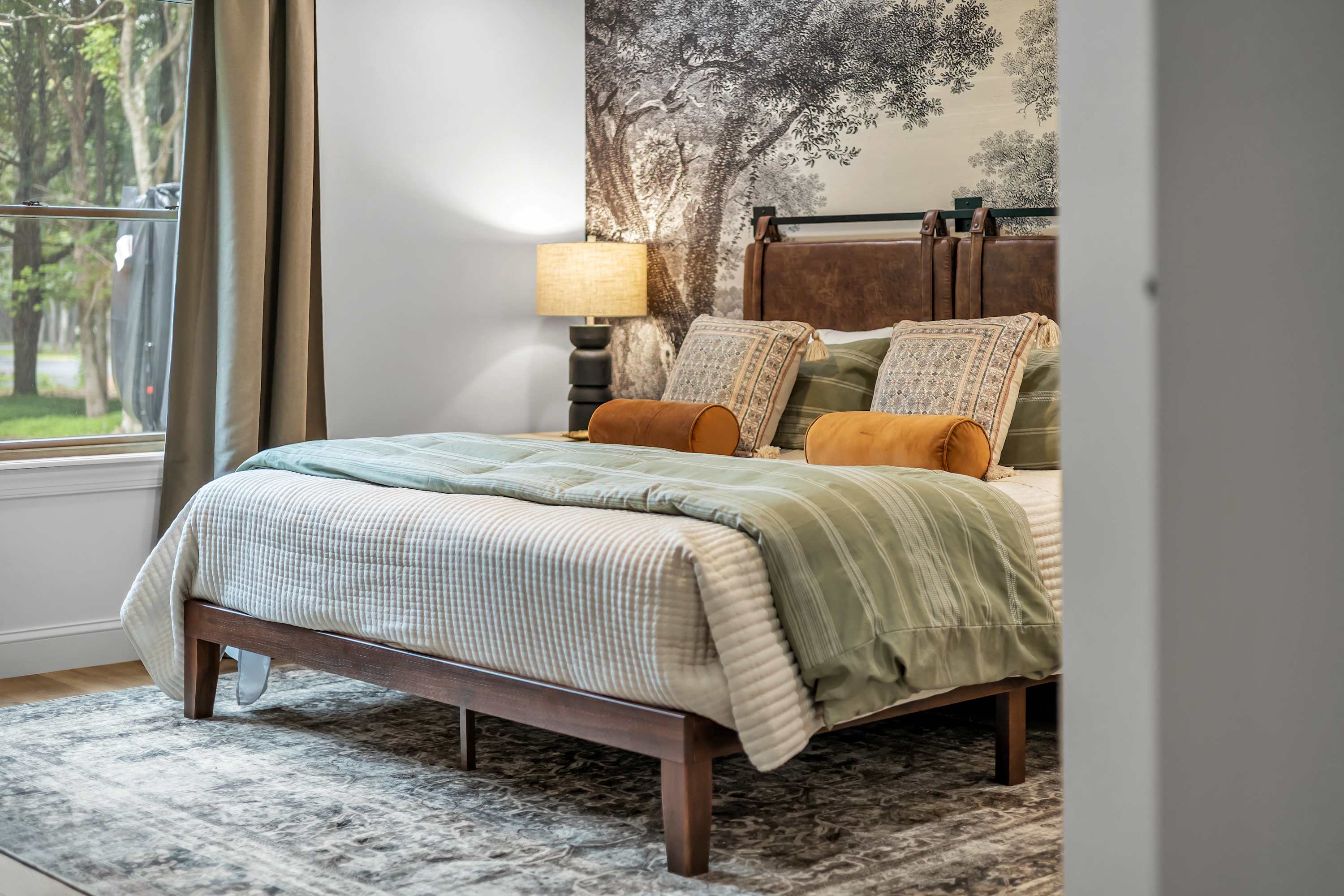 Nature-Inspired Second Bedroom – A beautifully designed space with a stunning mural accent wall, warm earth tones, and large windows bringing in natural light.