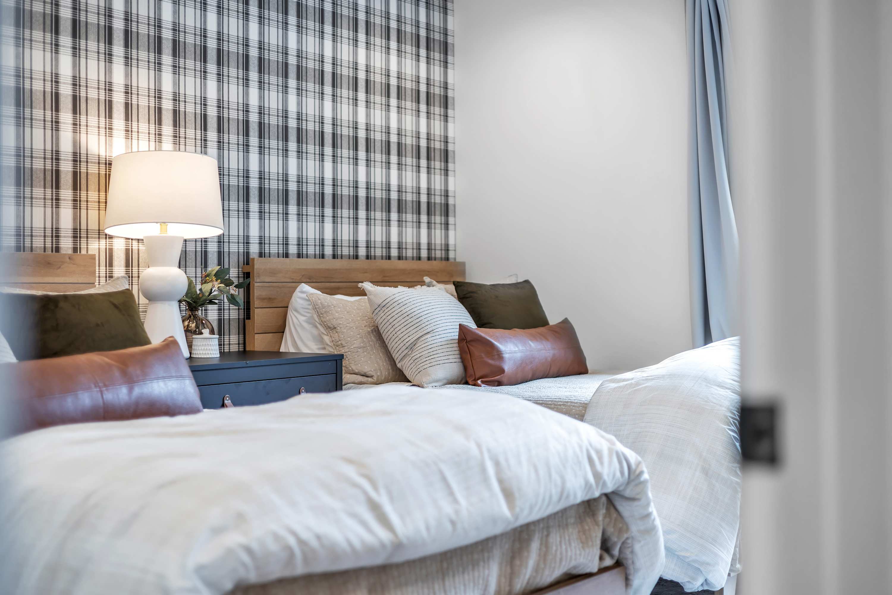 Cozy & Inviting Third Bedroom – Warm lighting, plaid accent walls, and plush bedding create a comfortable and stylish space for a restful night.