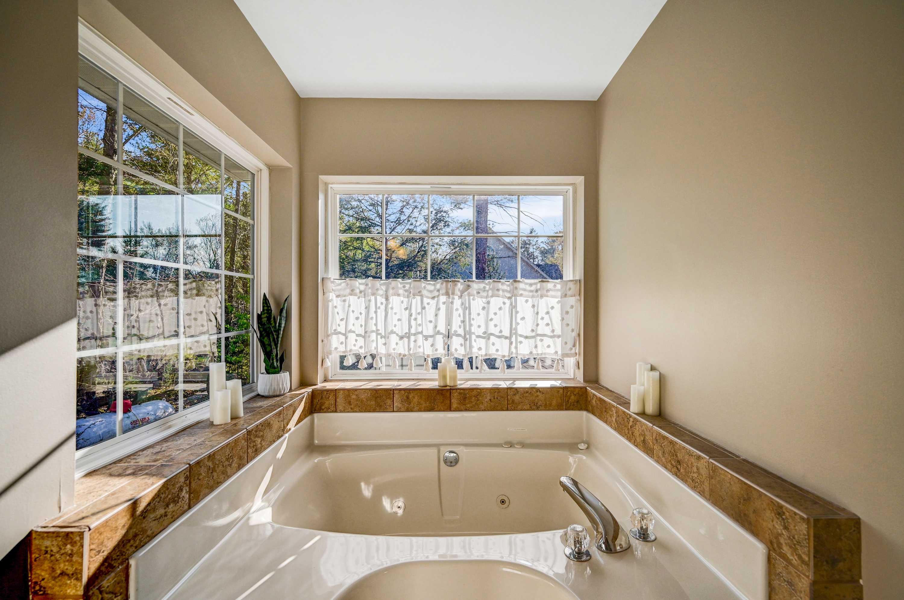 Bright, Airy & Elegant! With a stunning bathtub, chic decor, and large windows, this bathroom is your personal oasis for relaxation and comfort.
