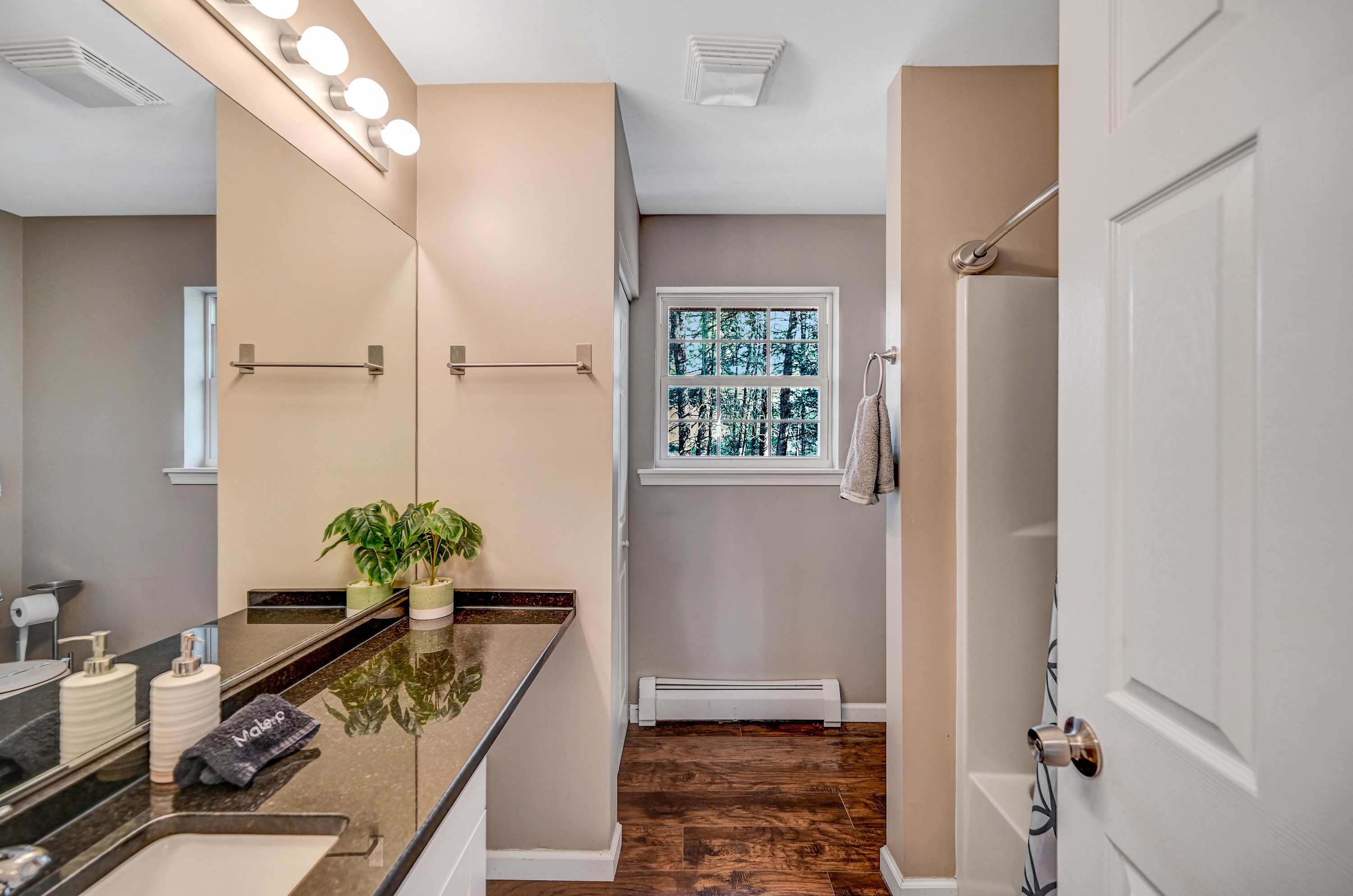 Bright & Refreshing! A sleek granite vanity, cozy lighting, and a tranquil window view, perfect for an energizing morning routine.