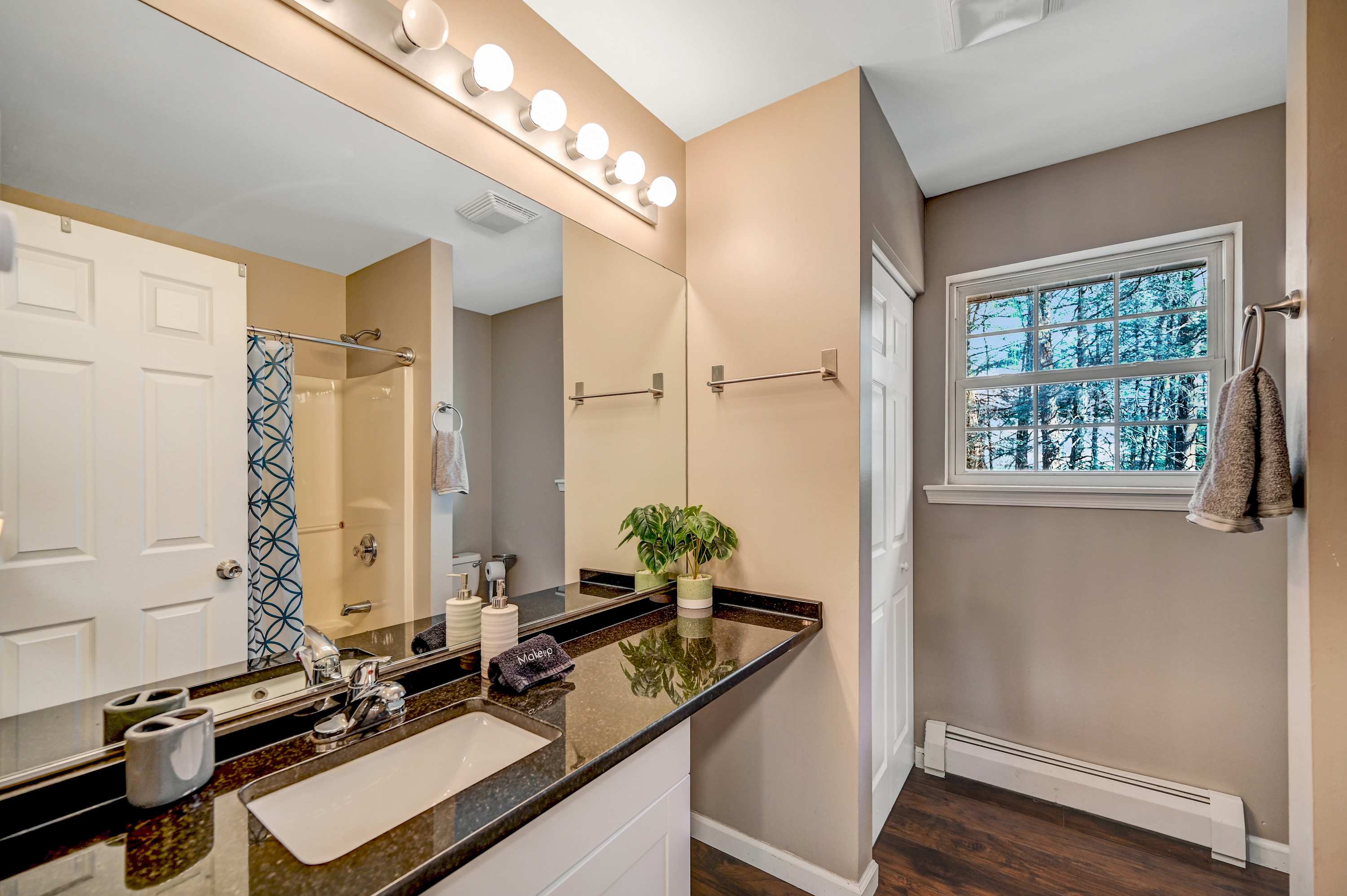 Bright & Functional! This well-lit bathroom features ample counter space, a spacious shower, and a serene window view.
