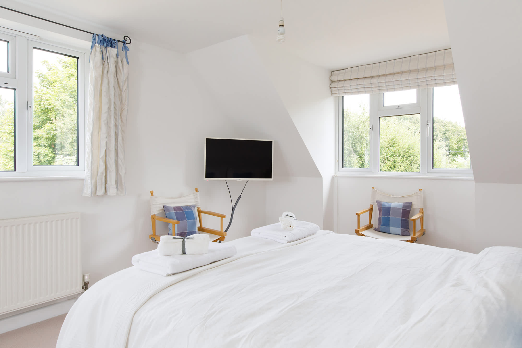 The master bedroom has a king bed, TV and two large windows looking out over the surrounding countryside.
