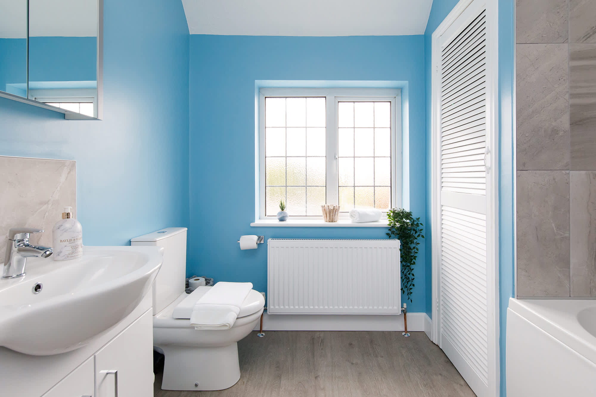 The large family bathroom has a bath with overhead shower, WC and sink.