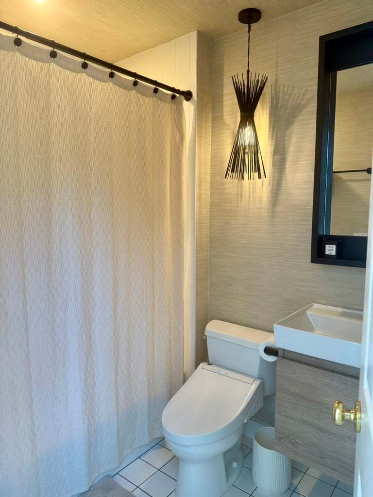 Bathroom with a pendant light, curtained shower-tub combo, and tiled flooring.