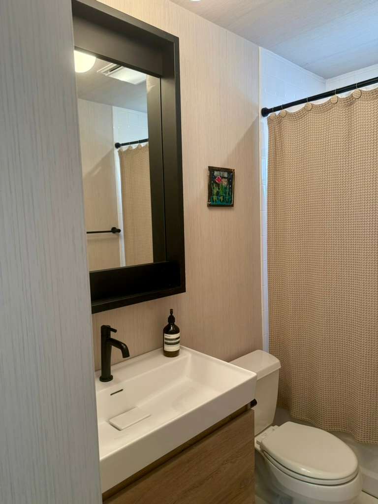 Bathroom with a wood vanity, wall-mounted mirror, and a shower-tub combo.