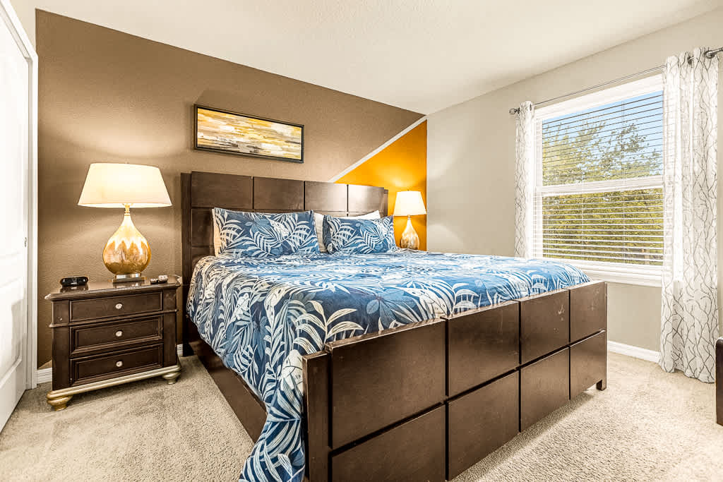 Relax in this cozy bedroom with tropical vibes, featuring a plush bed and abundant natural light.