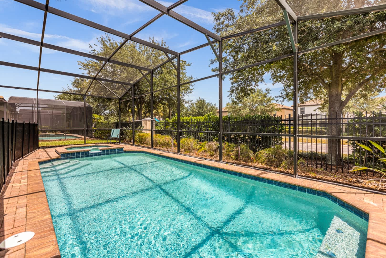 Enjoy a refreshing dip in your private screened pool, surrounded by lush greenery for a tranquil escape.