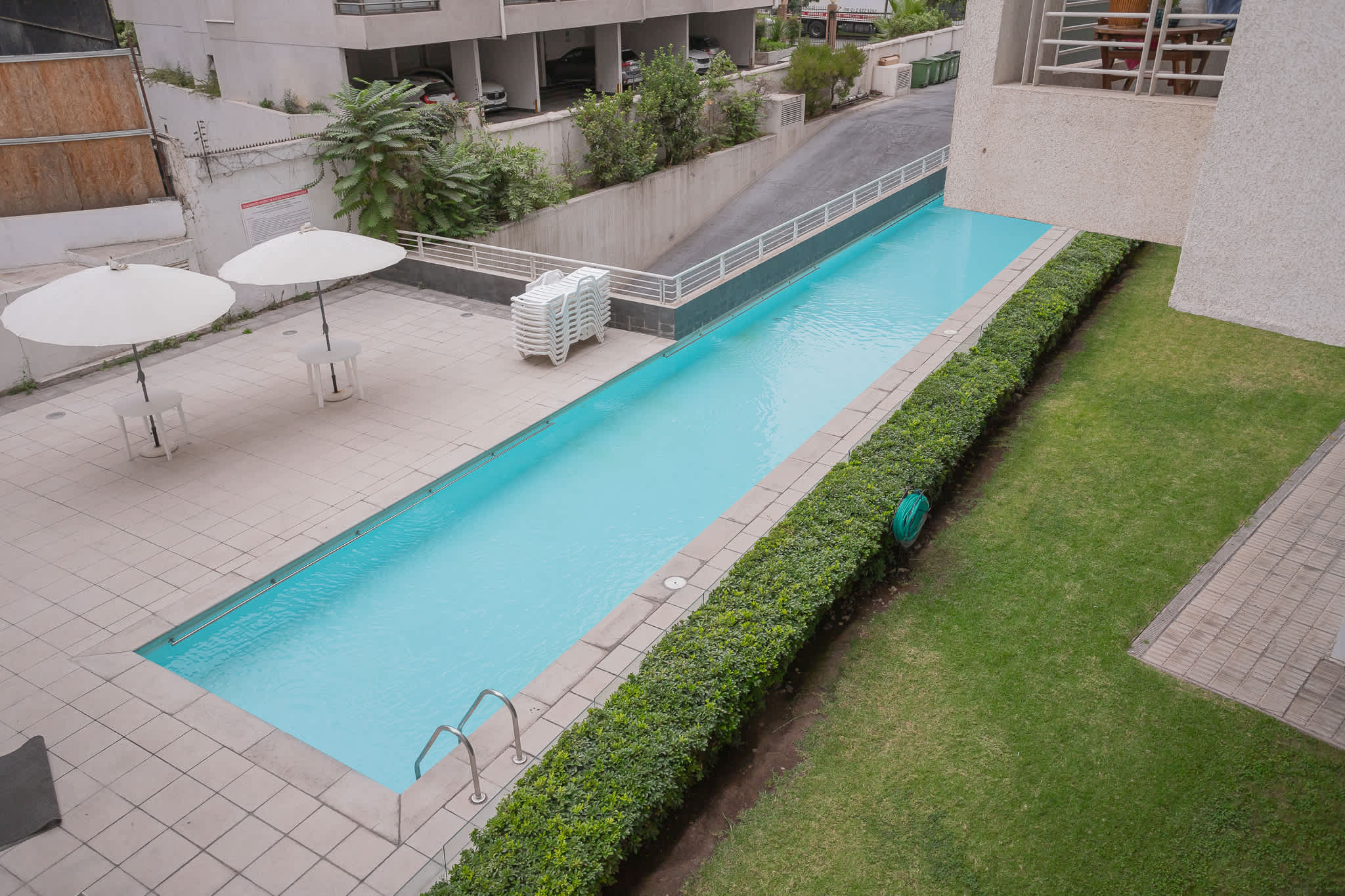 Relax by the serene poolside with ample seating and lush greenery. Sumérgete en un oasis de frescura bajo el sol