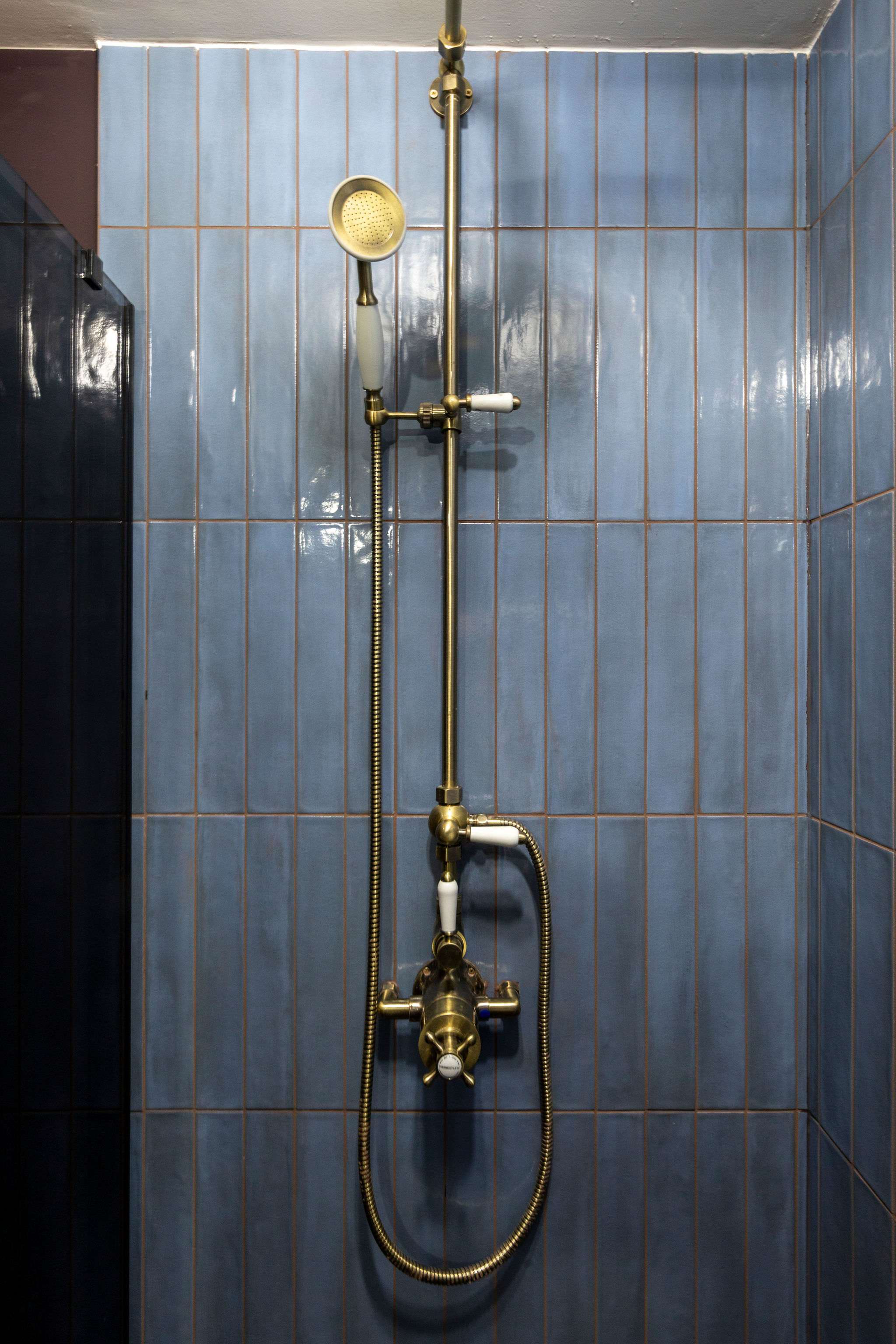 Relax in the spacious walk-in shower, featuring elegant gold fittings and tiled walls.