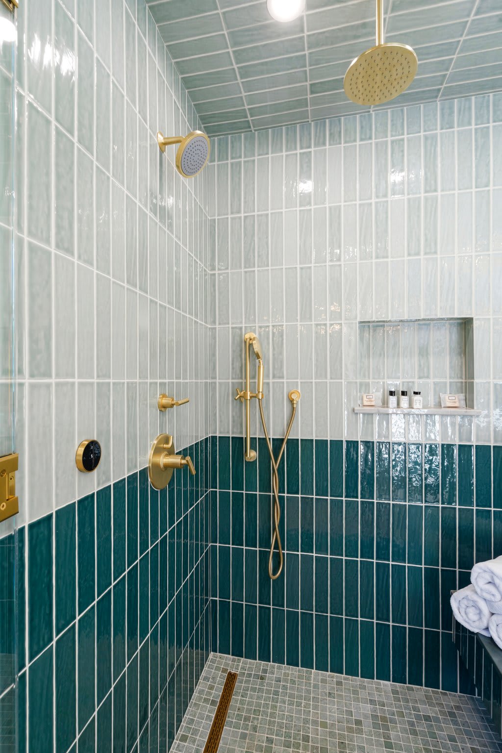 Step into a bold shower wrapped in deep green tile and luxe brass.