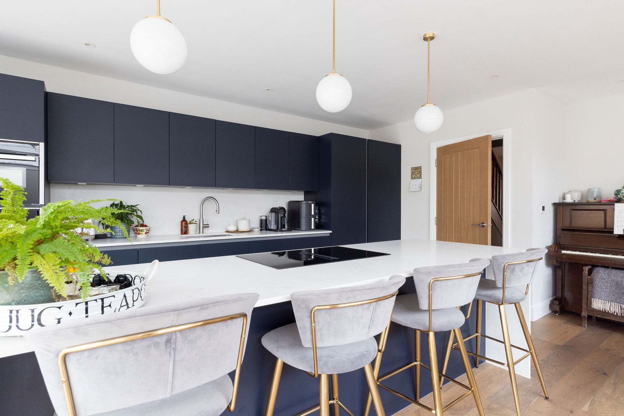 The fully-equipped kitchen and dining area boasts a minimalist design with modern appliances and large breakfast bar with wooden stool seating.