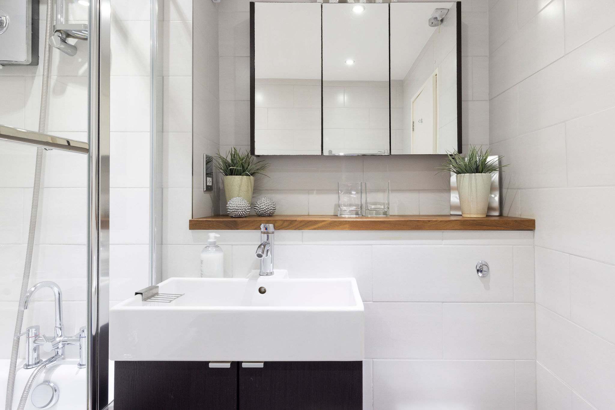 Bright and modern white-tiled bathroom with a sleek overhead mirror for the perfect start to your day.