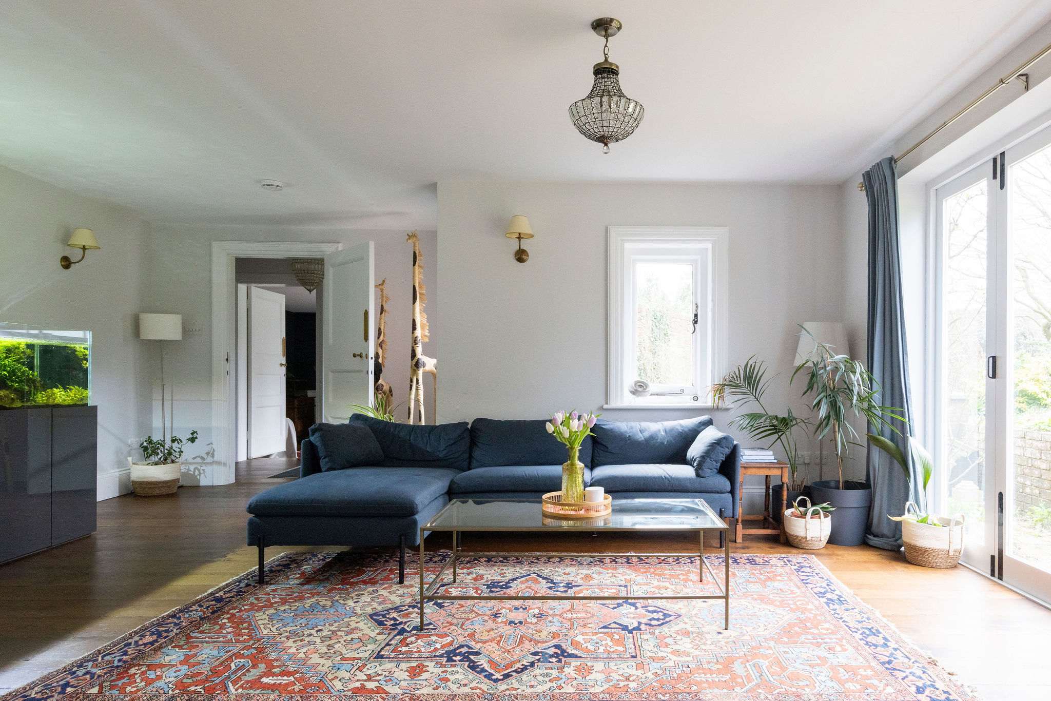 A stylish lounge with deep blue seating, large windows, and lush greenery