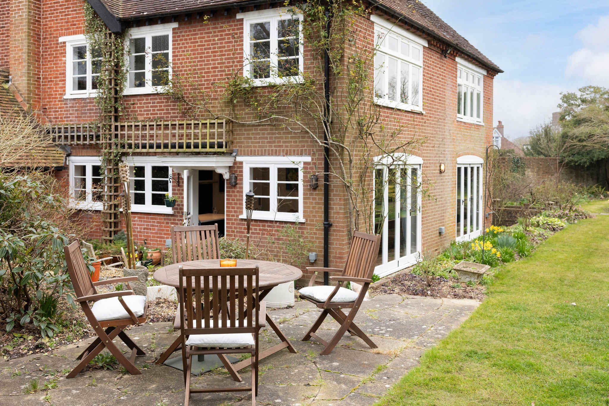 A charming brick home with lush greenery and an inviting outdoor dining area