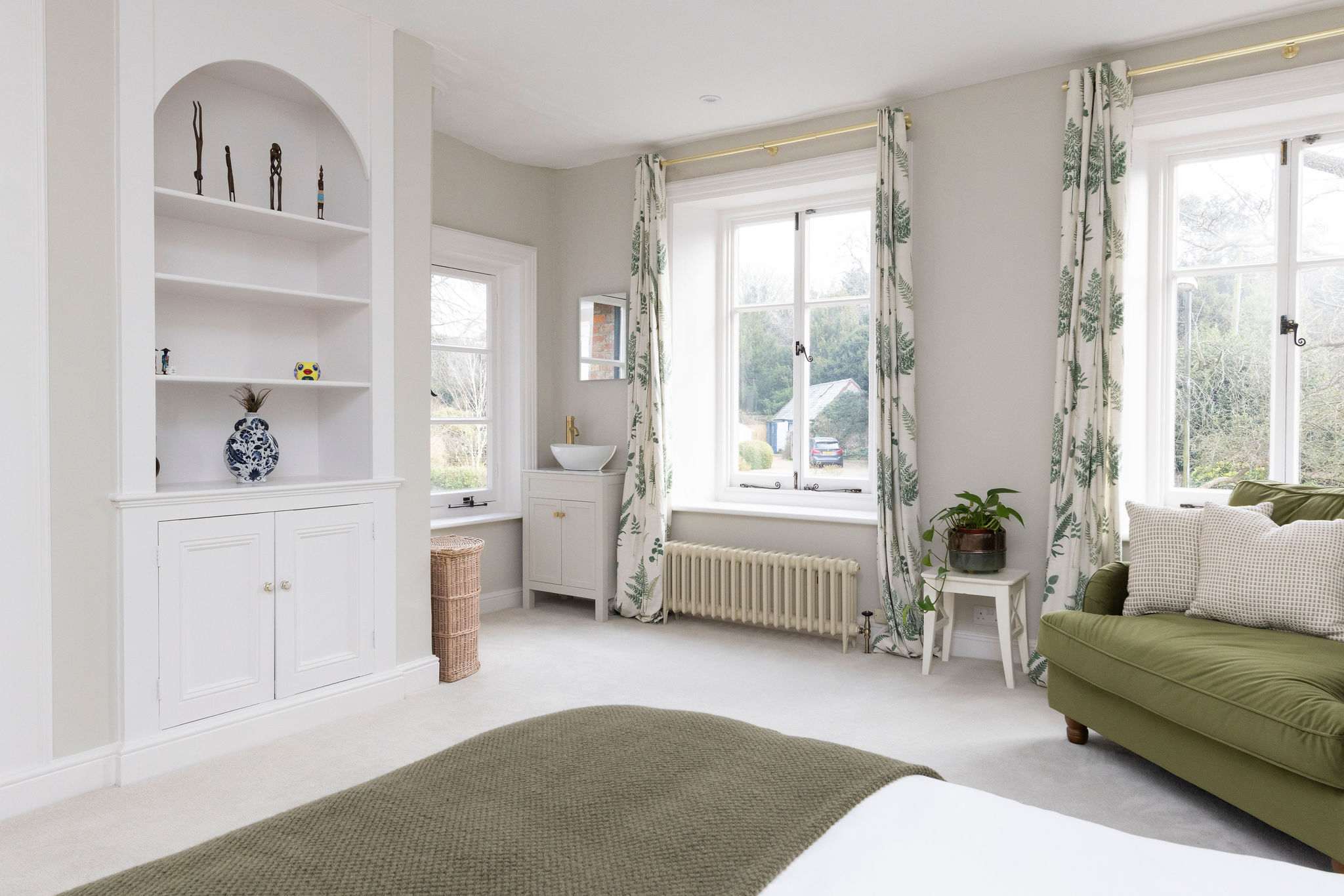 A light-filled bedroom with soft green accents and classic architectural details