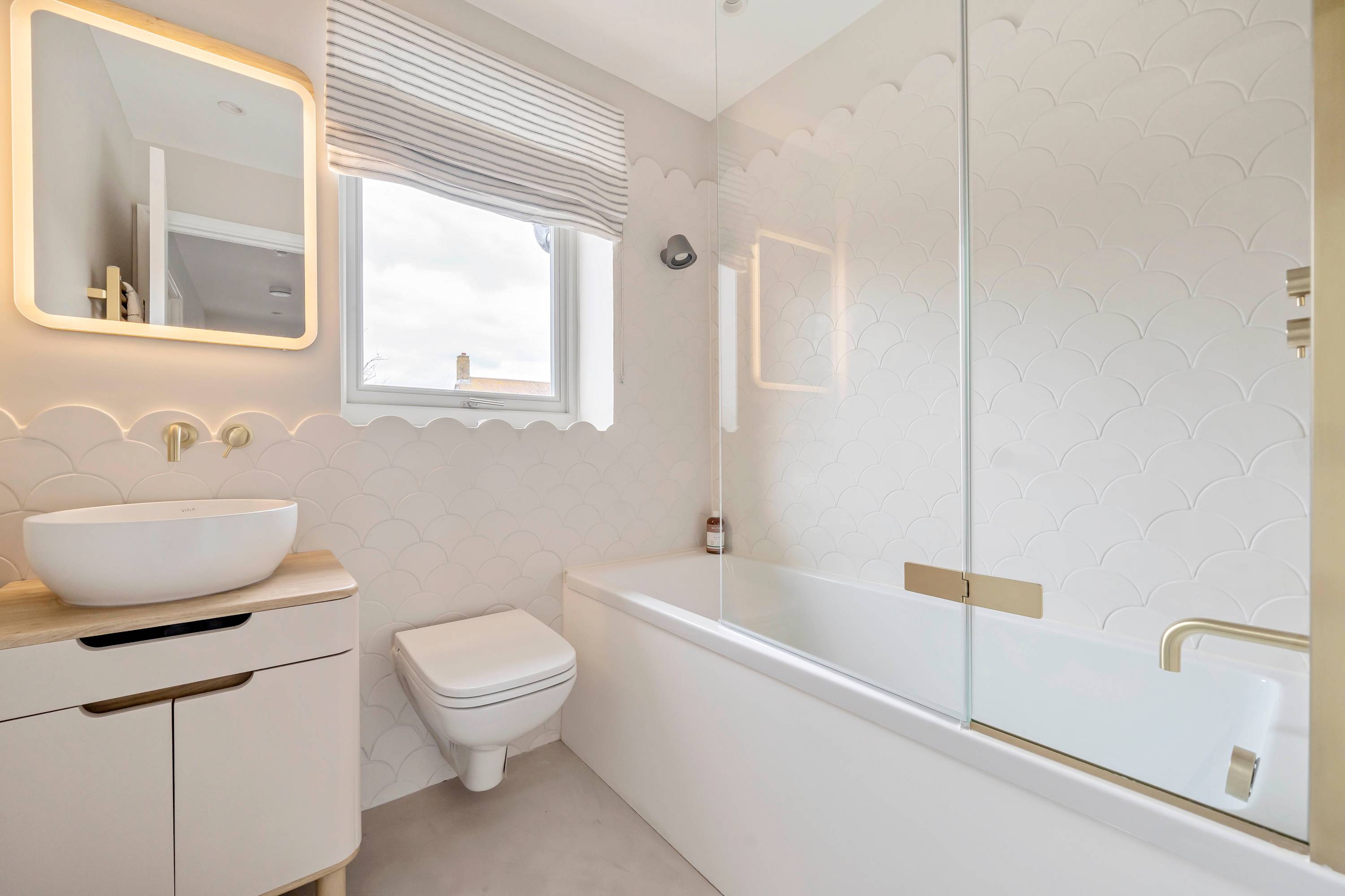 Freshen up in this sleek, spa-like bathroom featuring gold accents, a rainfall shower, and plenty of natural light.