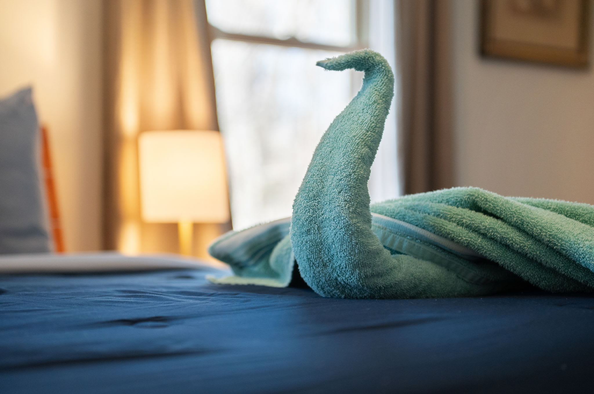 A charming towel swan welcomes you to the beautifully made master bed