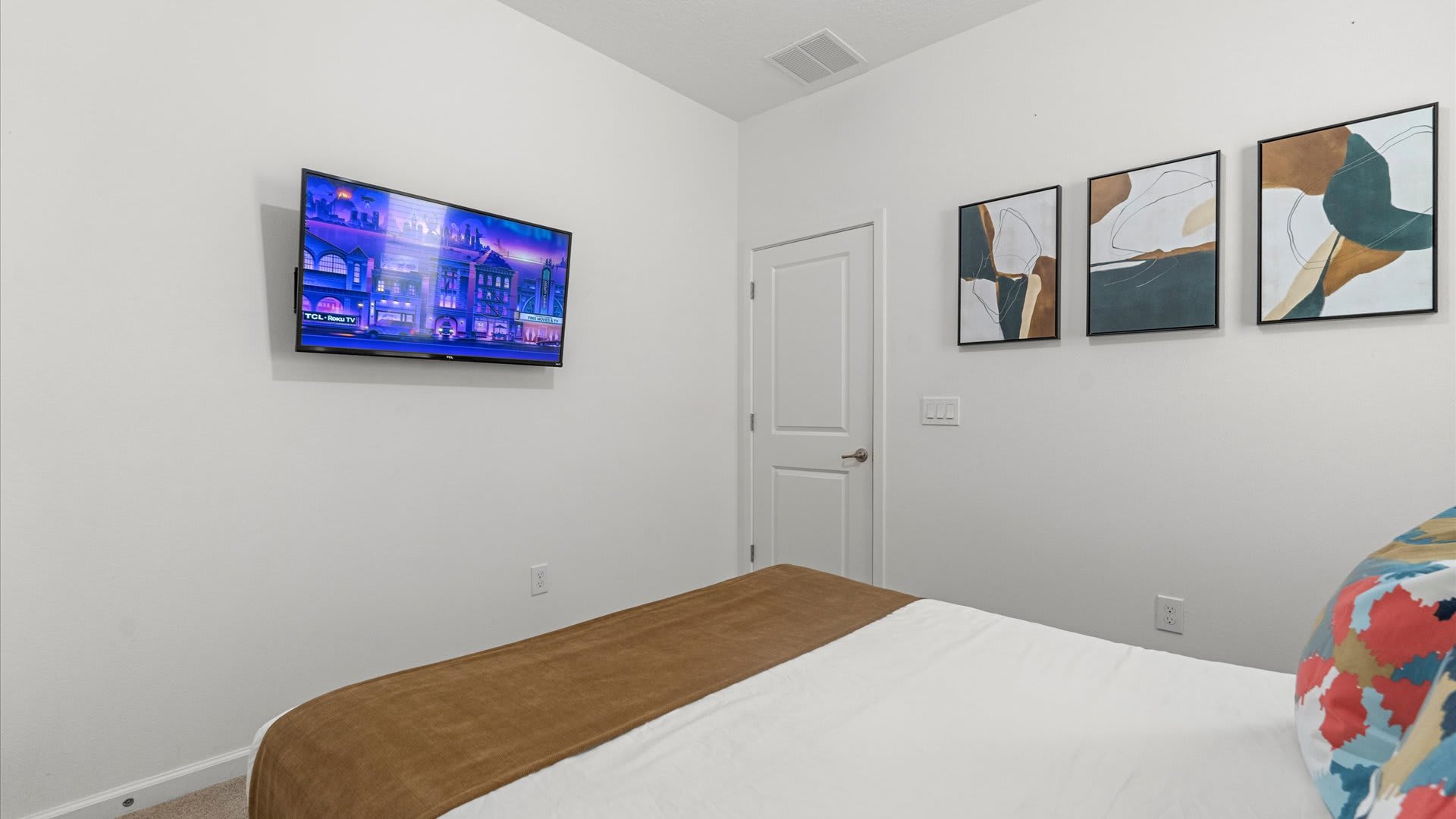 Comfortable Bedroom Featuring A Sleek Bed Frame And Wall-Mounted Smart TV