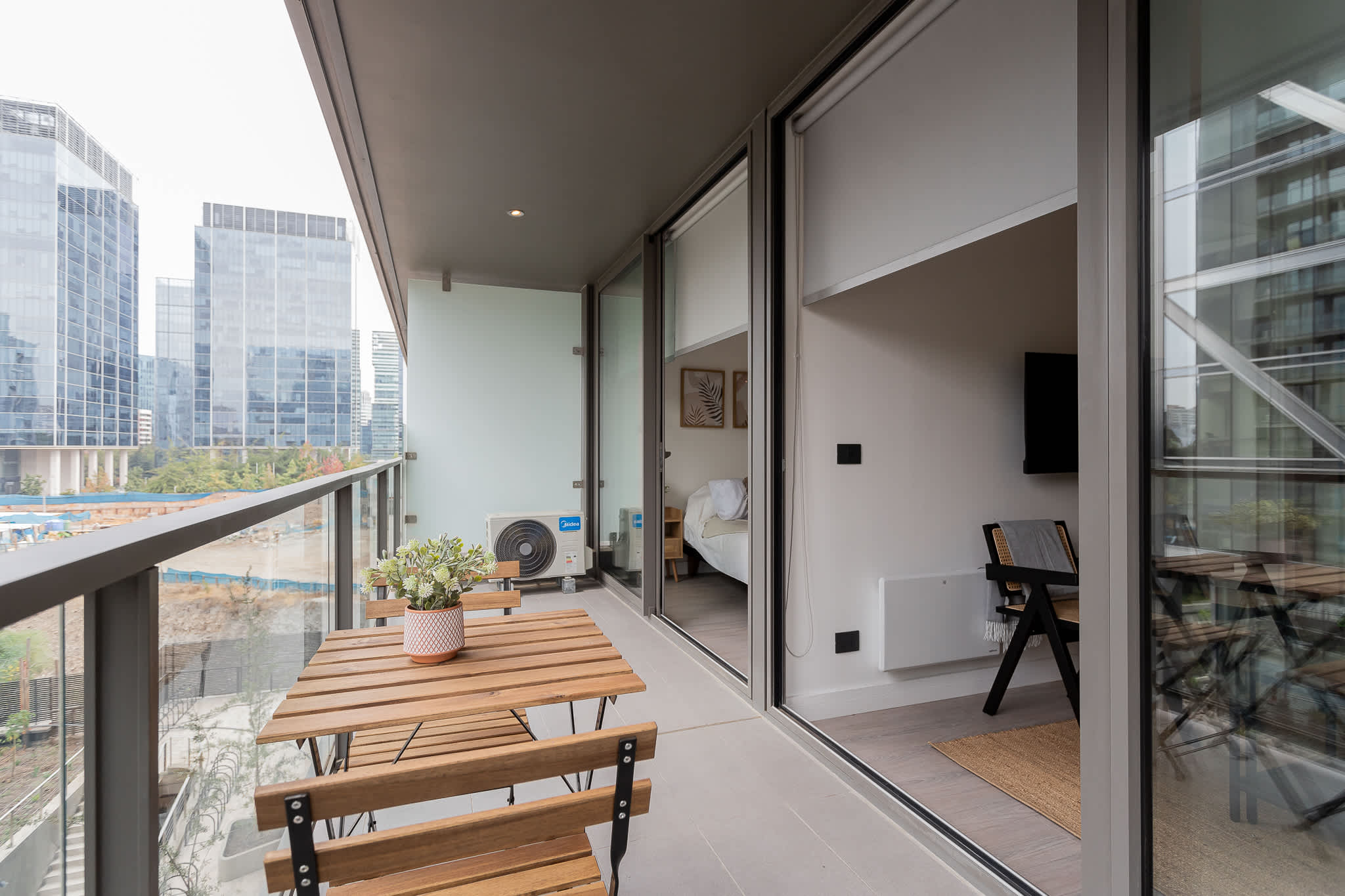 Enjoy a modern urban retreat on this spacious balcony, perfect for relaxing with a view of the city skyline.