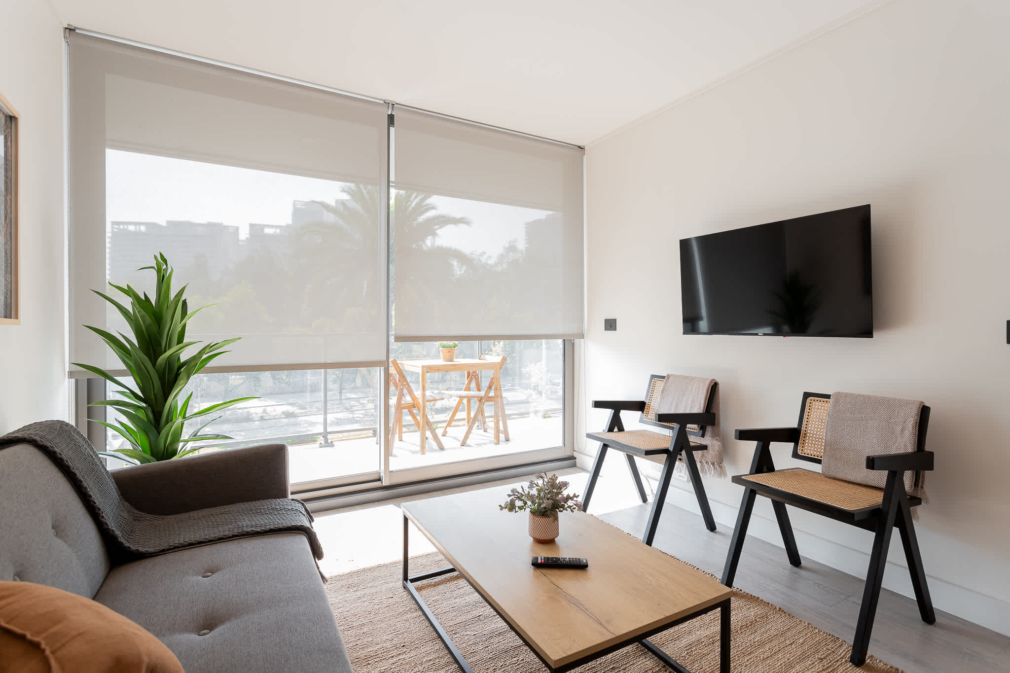 Relax in a bright, modern living room with large windows and a view of lush greenery. Enjoy the comfort and style of this inviting space.