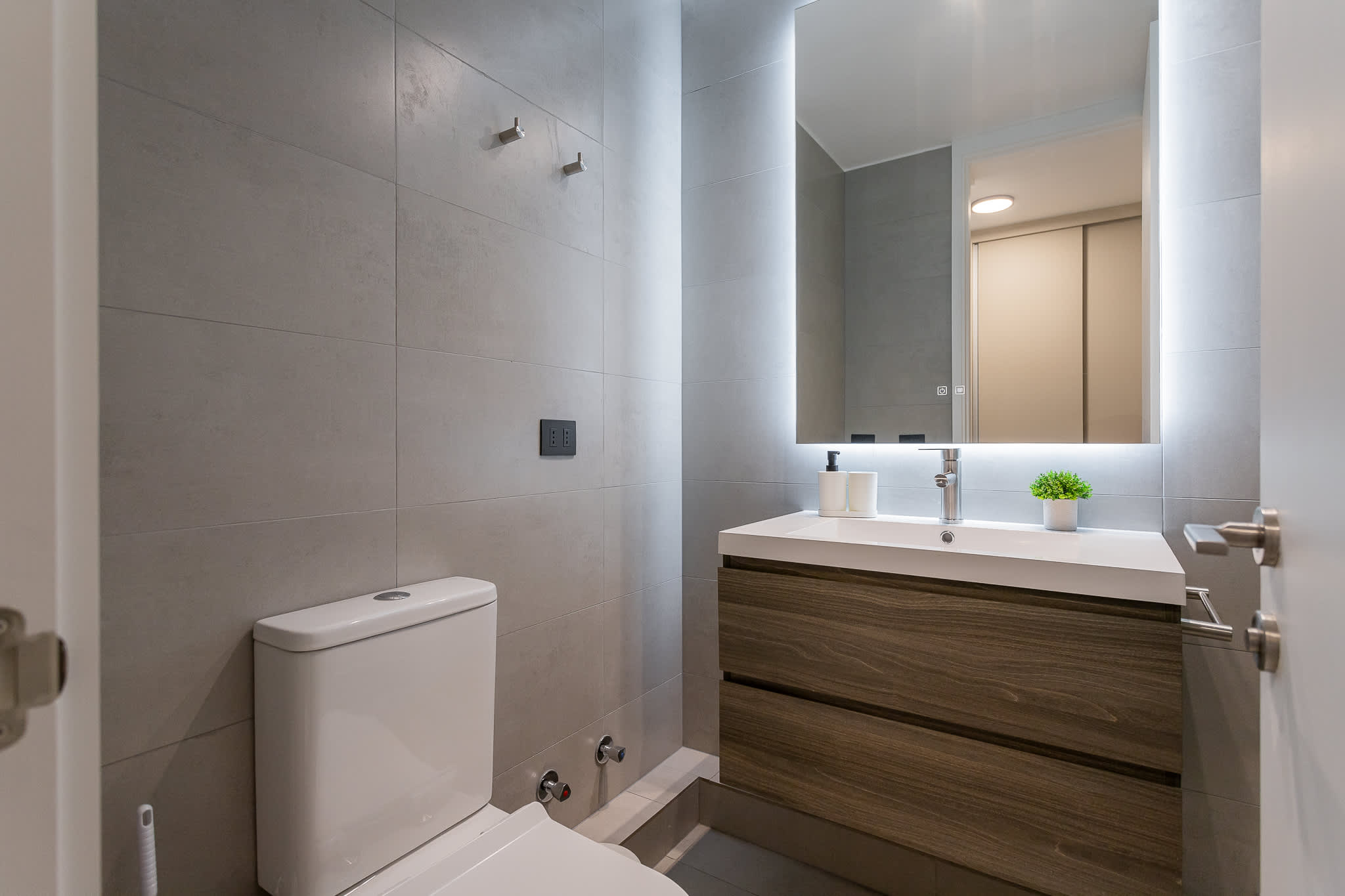 Experience a sleek and modern bathroom with stylish finishes and a touch of greenery for a refreshing stay.