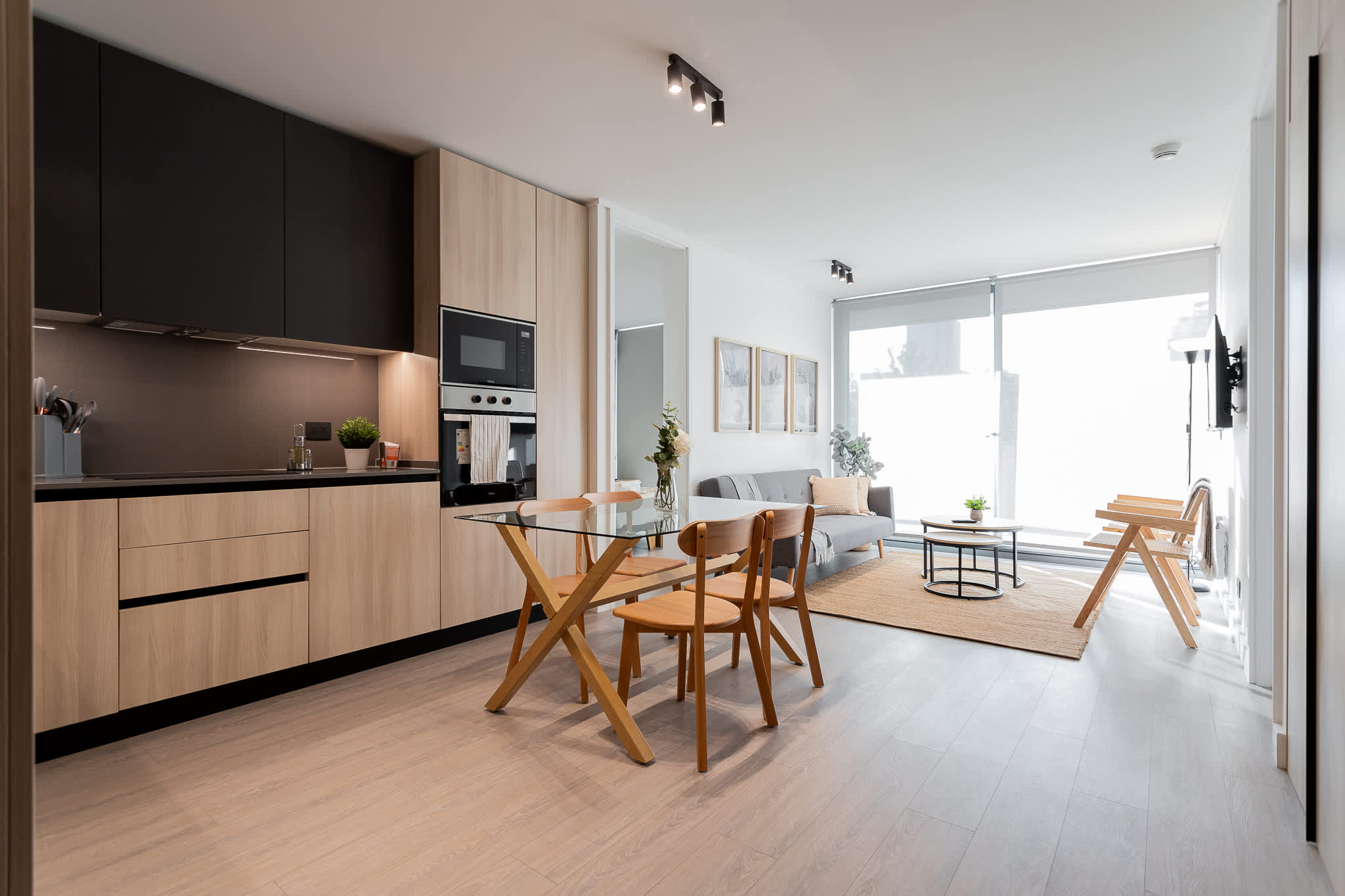 Modern and cozy open-plan living space with a sleek kitchen and abundant natural light, perfect for relaxation and dining.