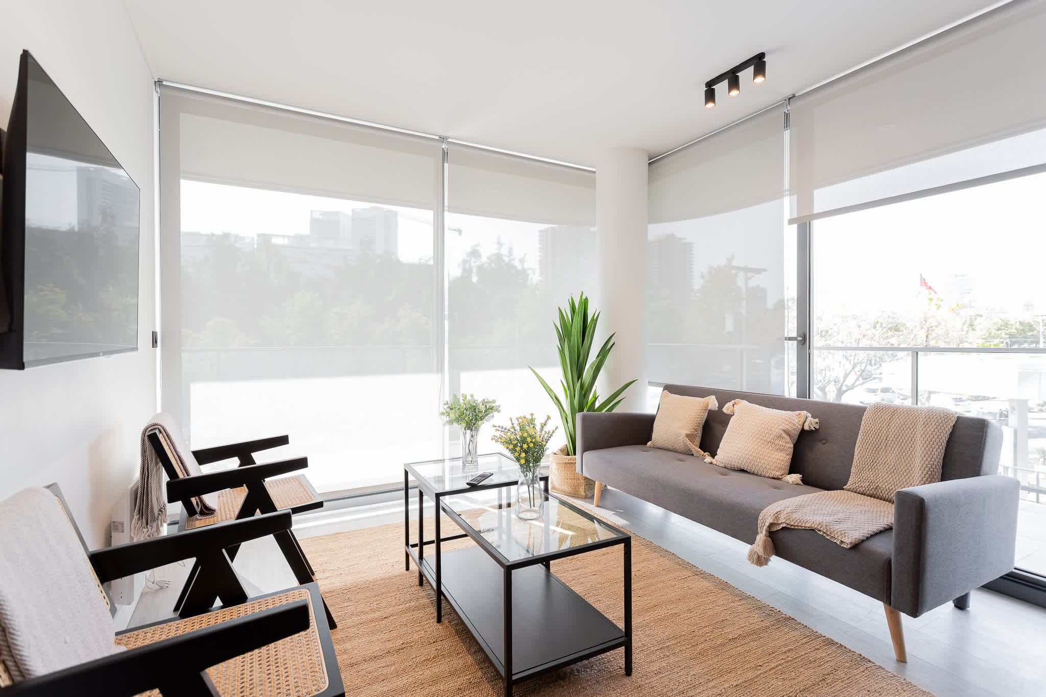 Bright and modern living room with a cozy sofa, stylish decor, and expansive windows offering a stunning city view.
