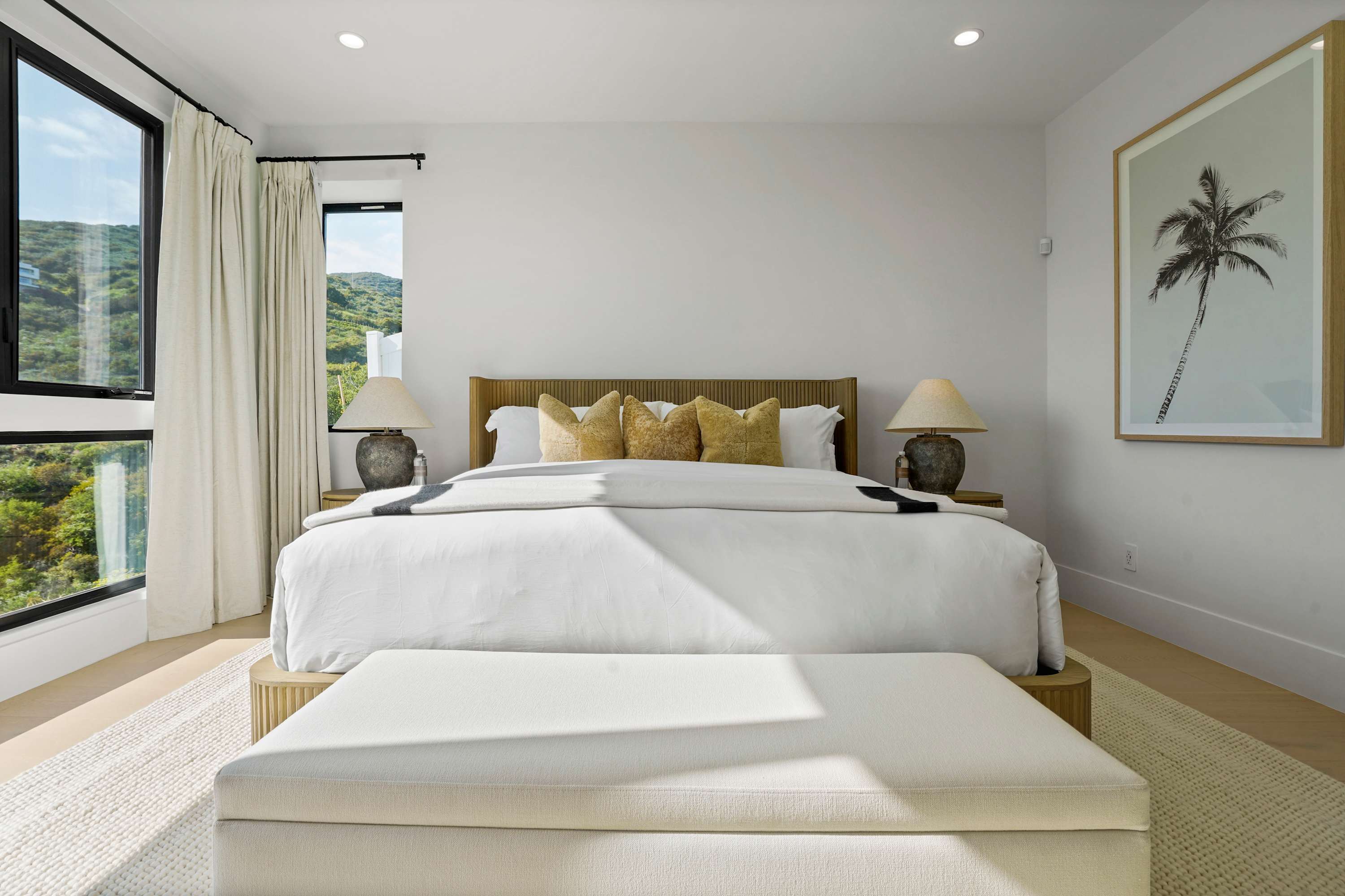 Primary bedroom featuring a king bed, hill views, blackout curtains, and neutral decor.