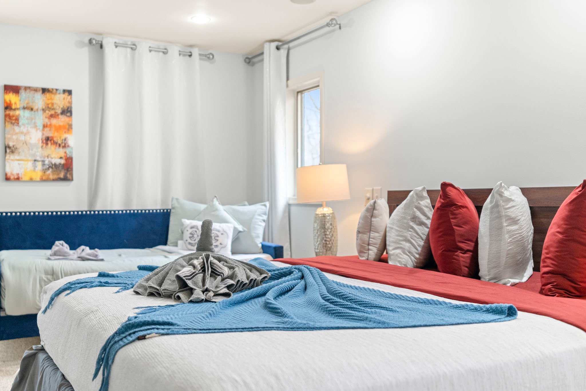 Soft Tones and Bold Accents
Bright whites with pops of red and blue make this bedroom feel fresh, fun, and inviting.
