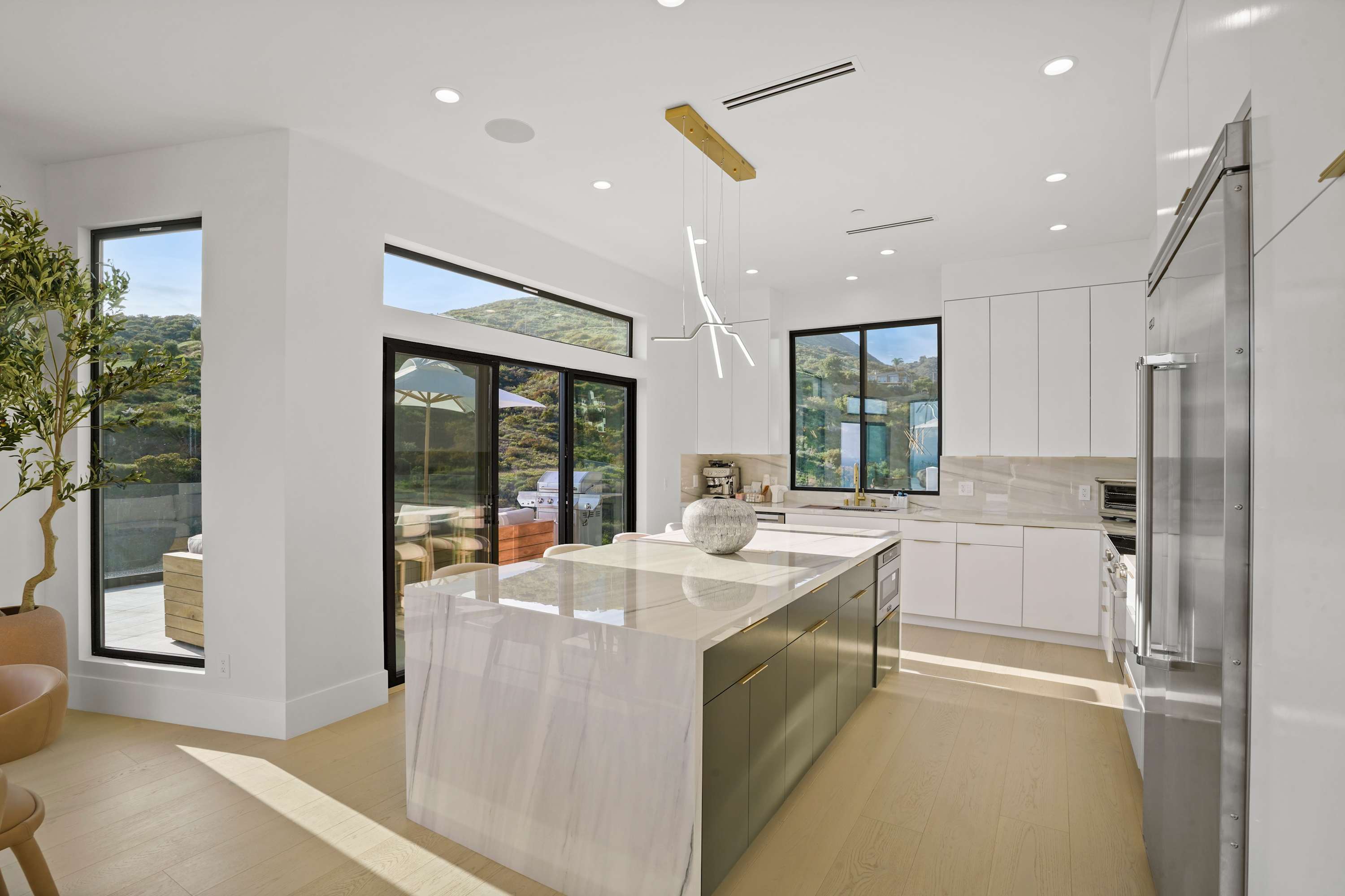 Contemporary open kitchen with floor-to-ceiling white cabinetry and honed marble countertops