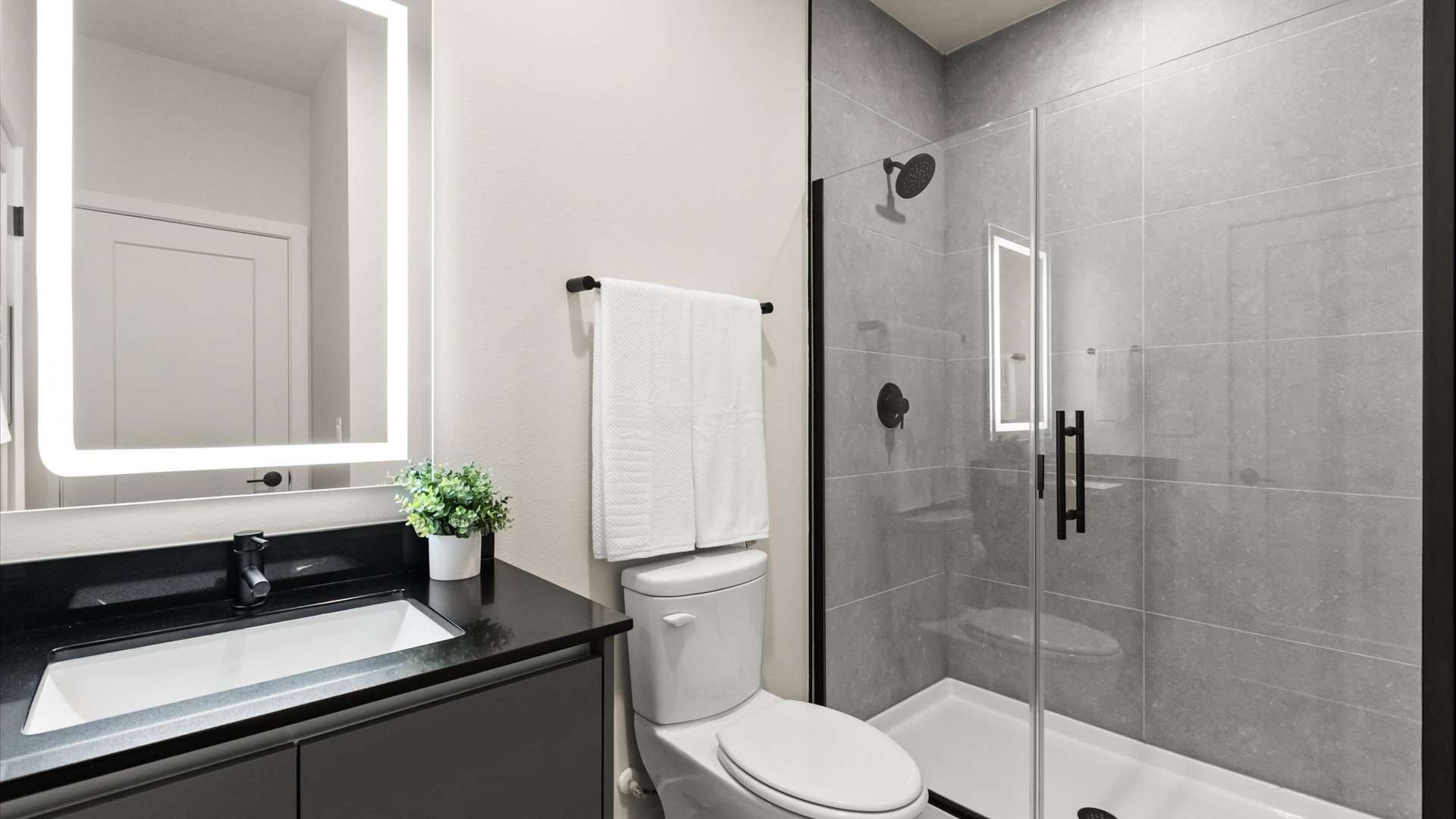 Modern full bathroom with standing shower and chic vanity with LED mirror