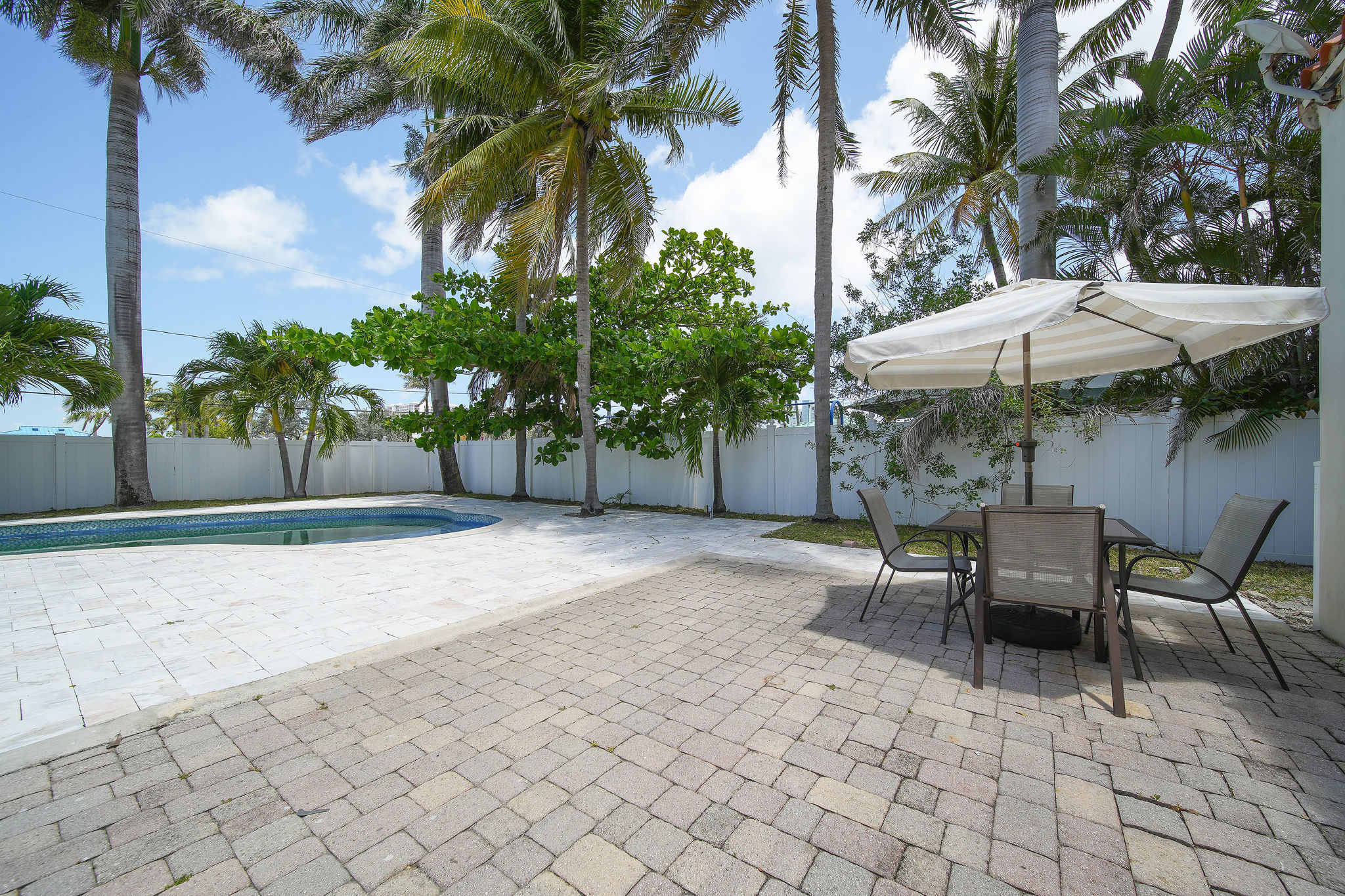 Enjoy a serene retreat by the pool under swaying palms, perfect for sunbathing or dining al fresco.